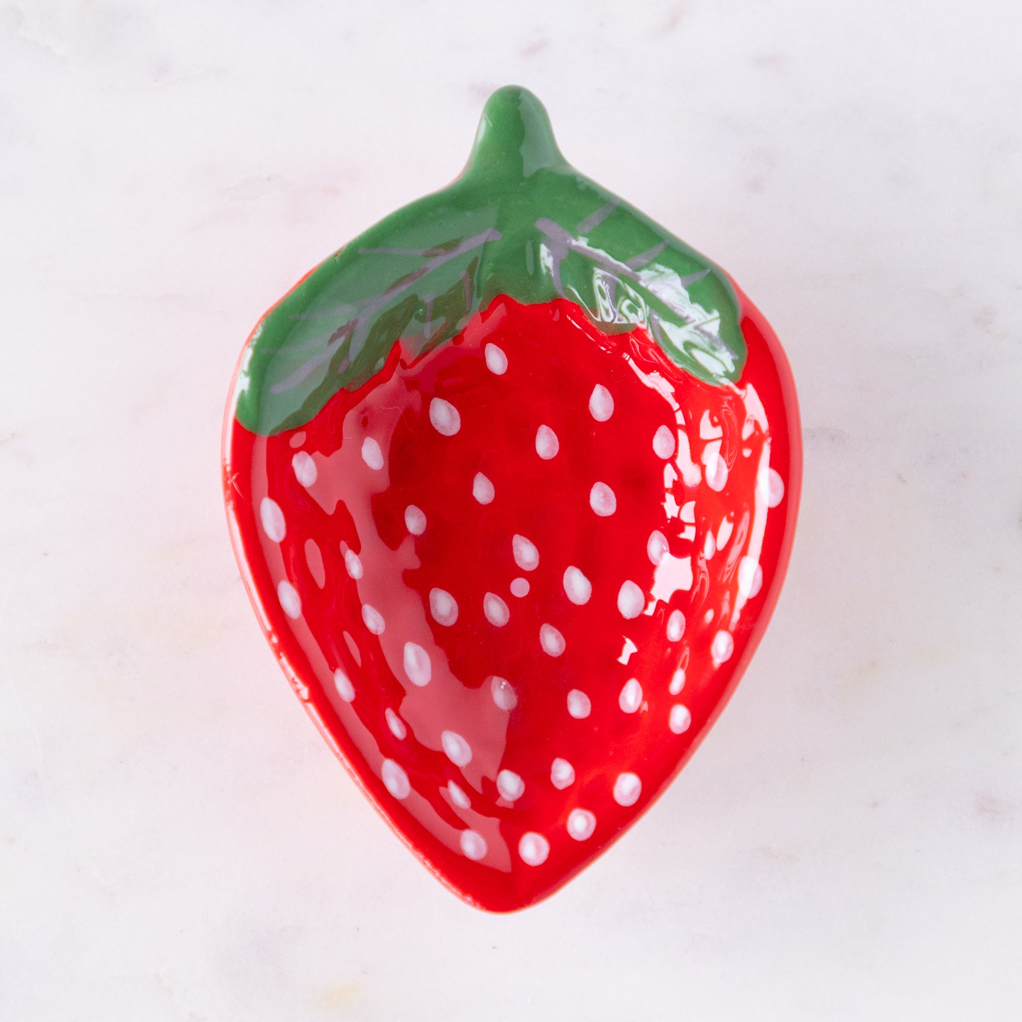 Red ceramic strawberry-shaped dish with green top on a white background.