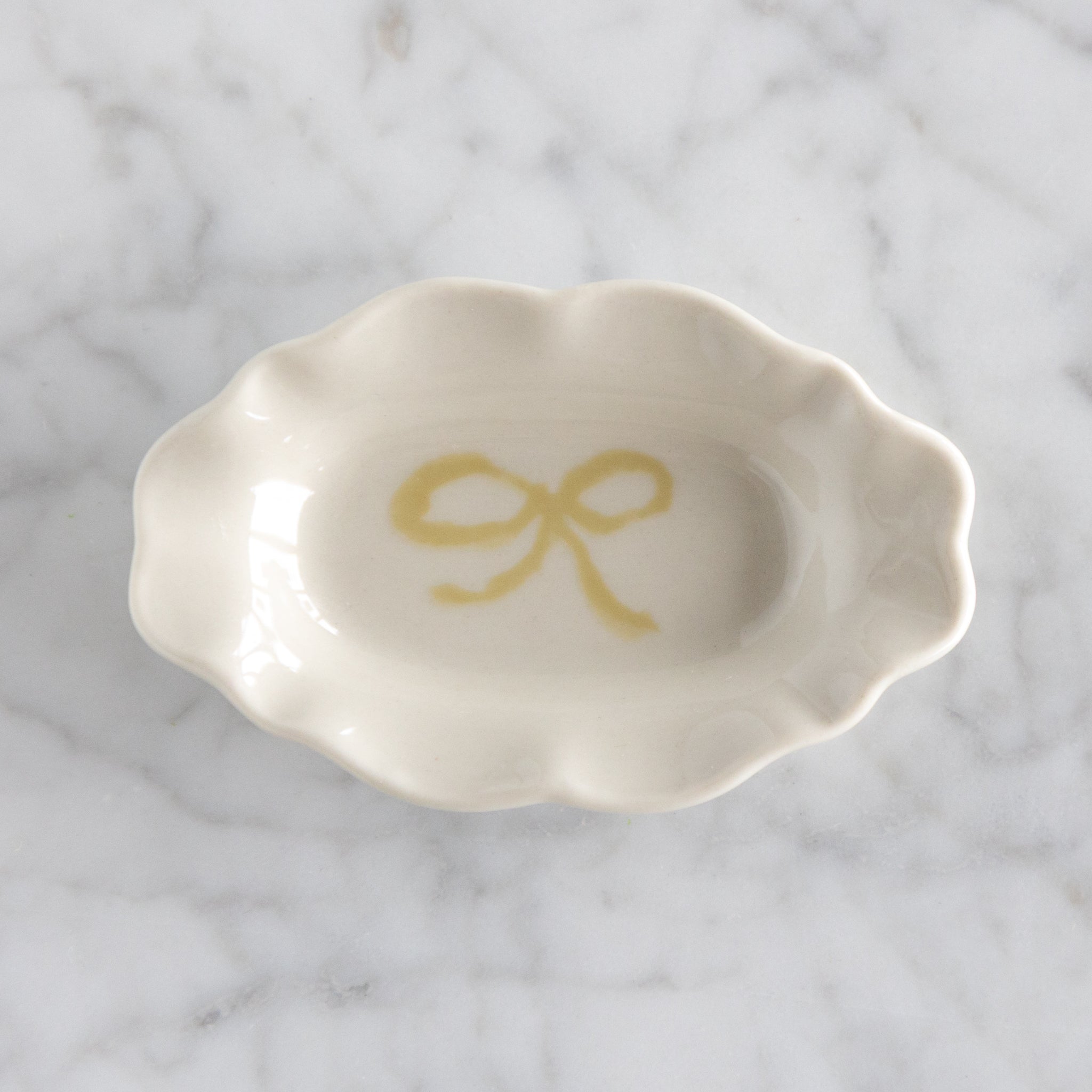 White ceramic dish with a yellow bow design on a marble surface.