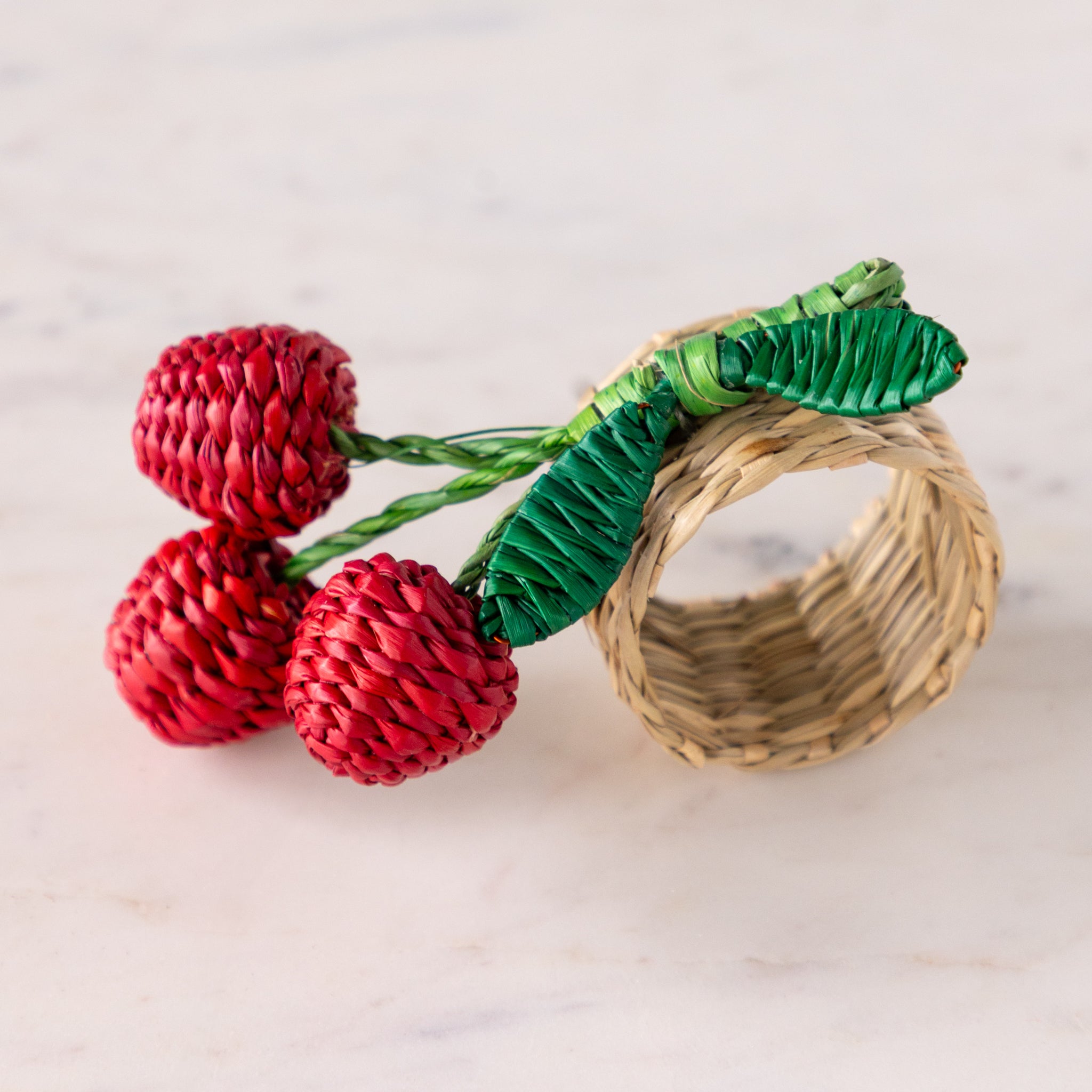 Woven Seagrass Cherry Napkin Ring on a marble table.