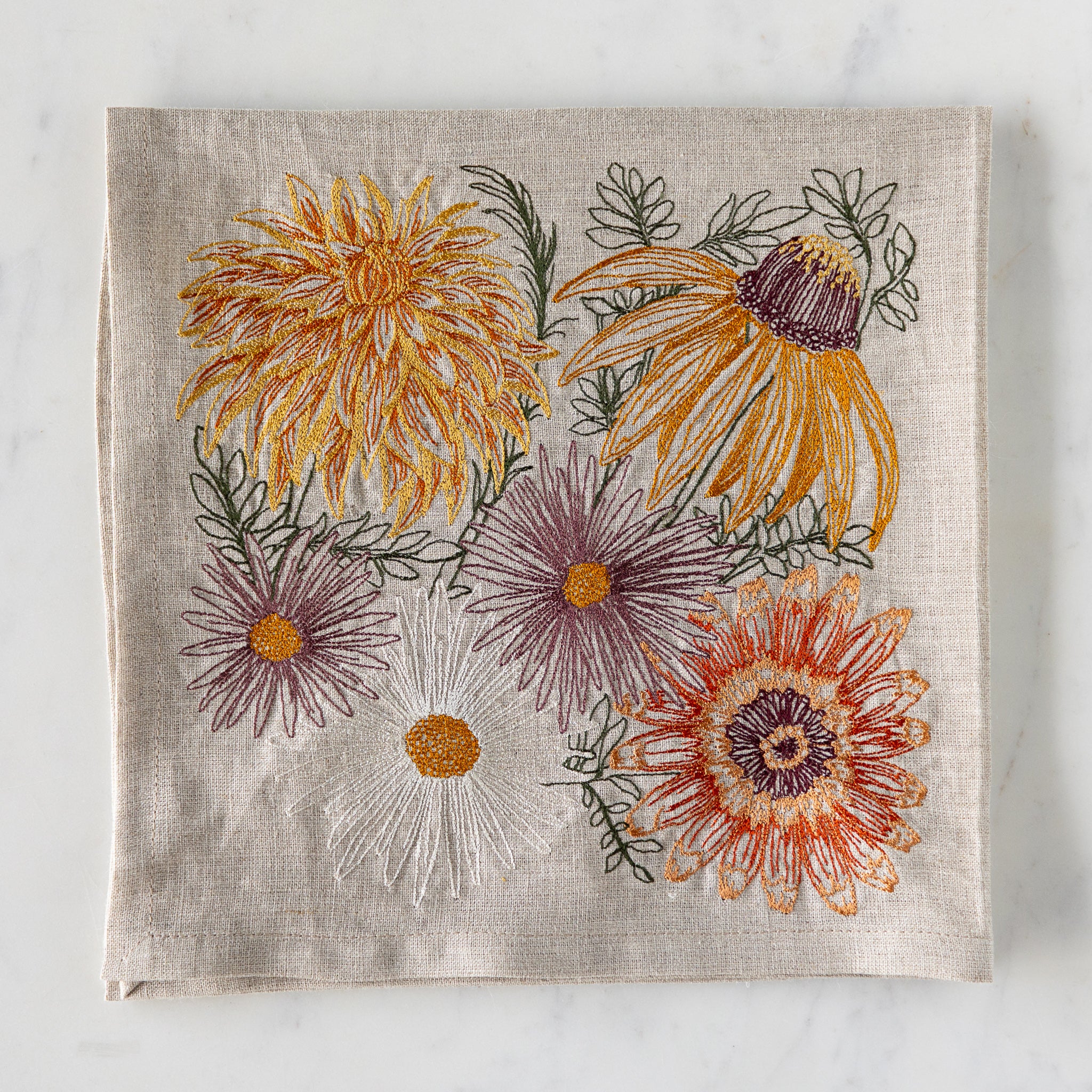 Autumn Blossoms Dinner Napkin folded on a marble table.