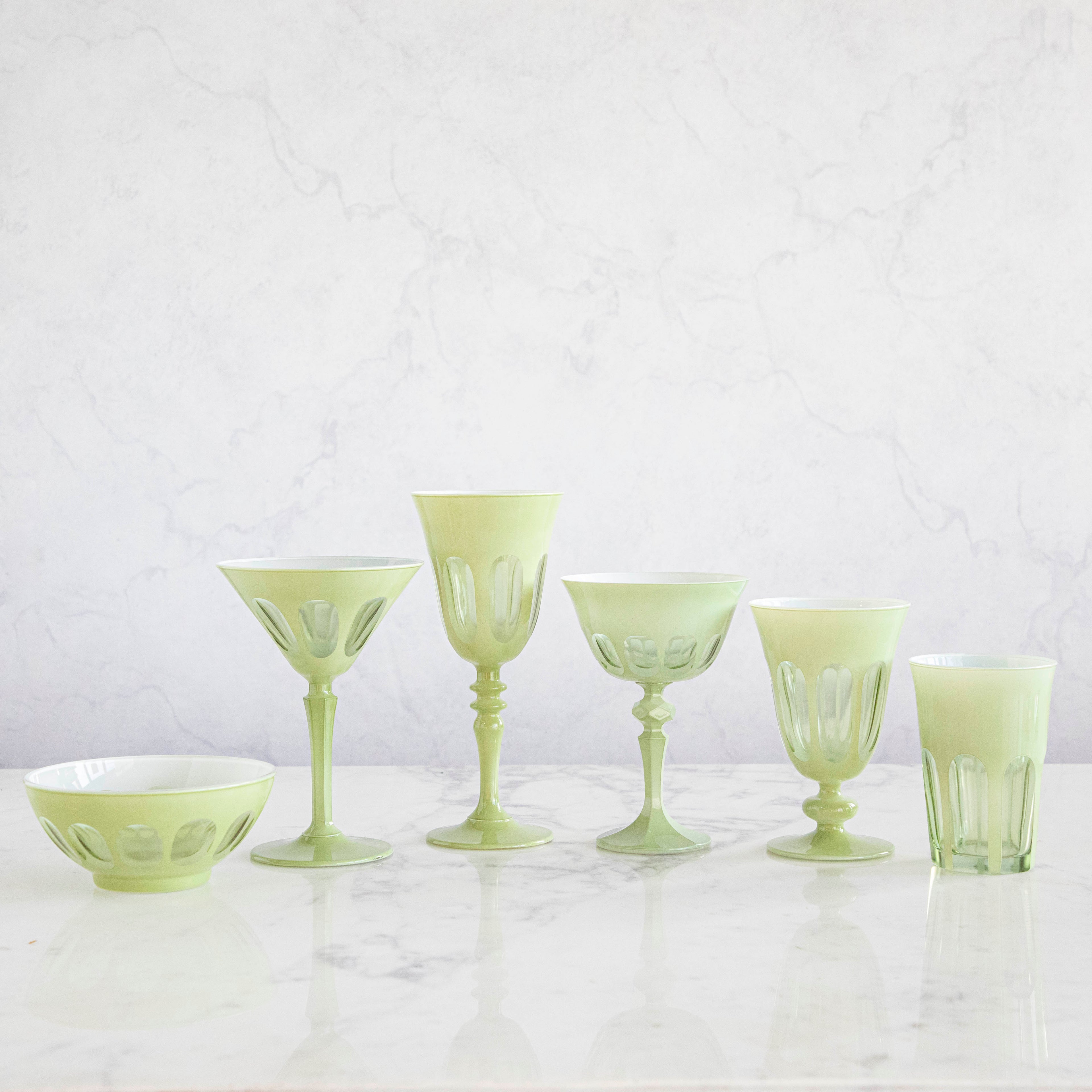 A set of SIR/MADAM Rialto Pale Sage Glasses and a bowl on a marble table.