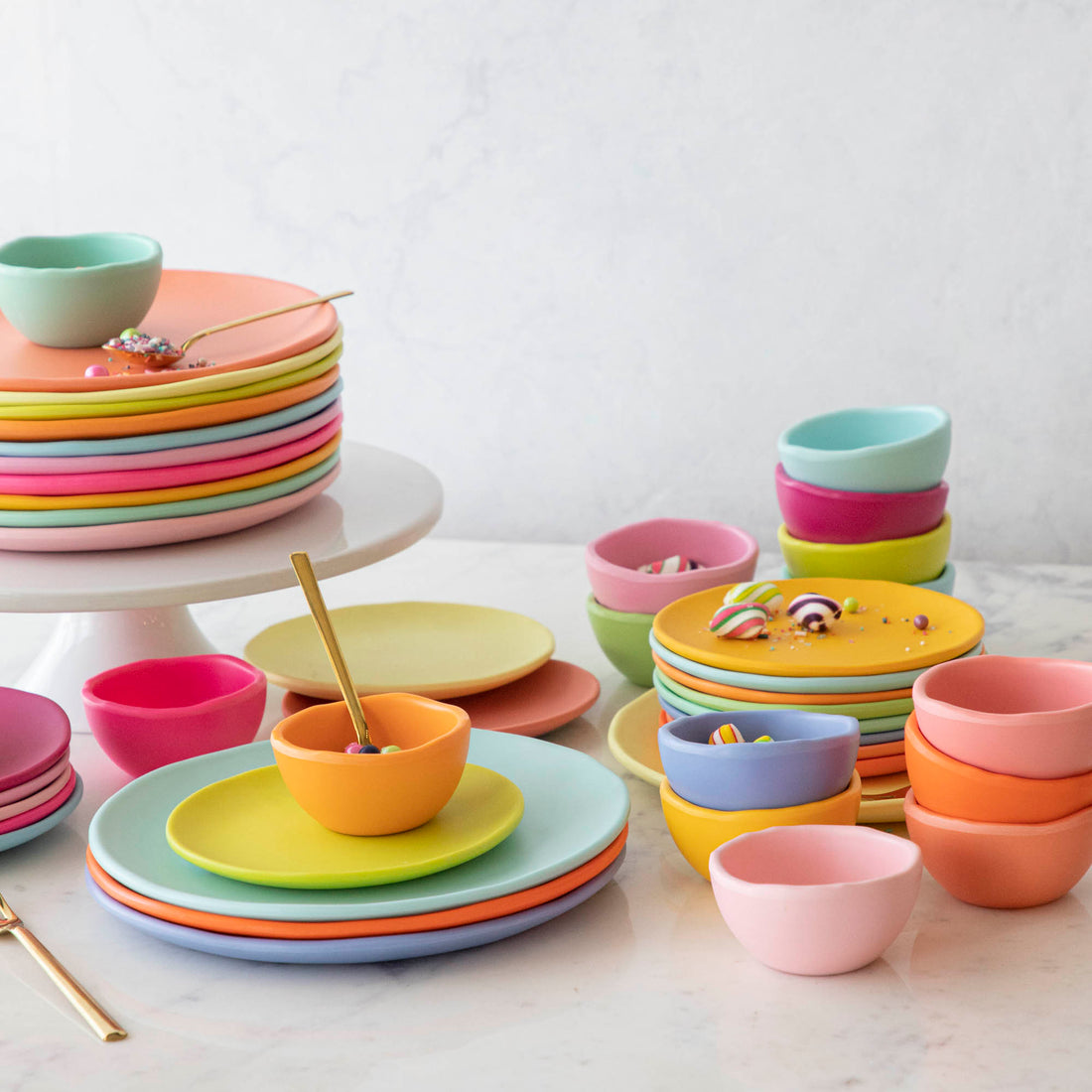 A stack of colorful plates and bowls on a white table.