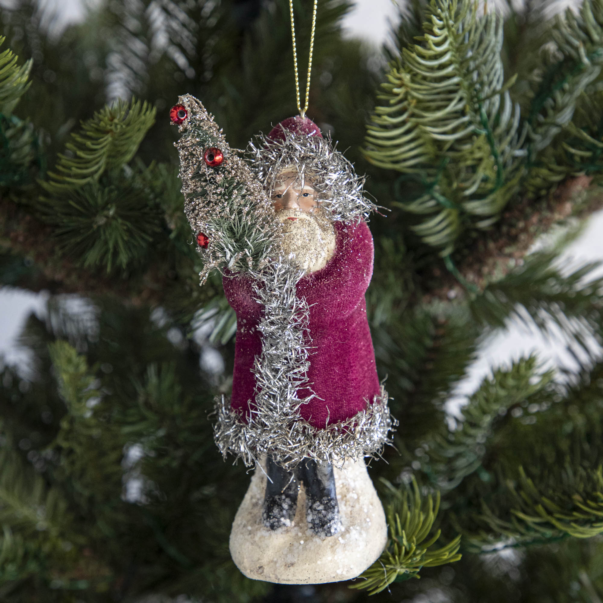 A pink-robed Santa Claus ornament on a tree.