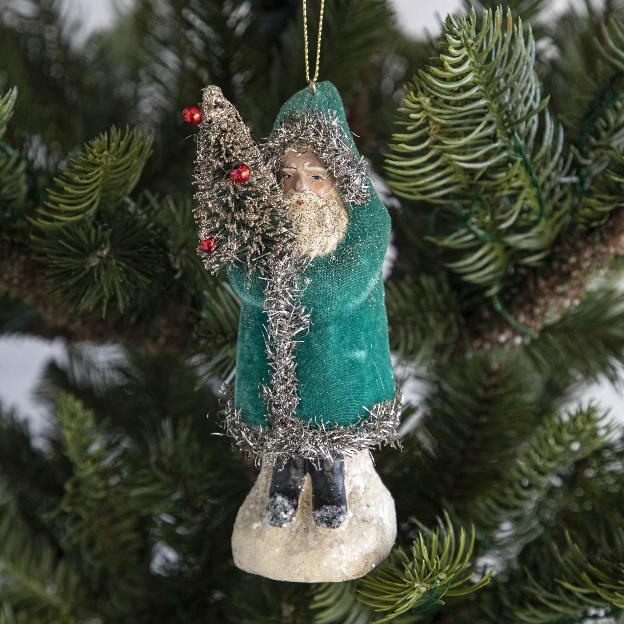 A teal-robed Santa Claus ornament on a tree.