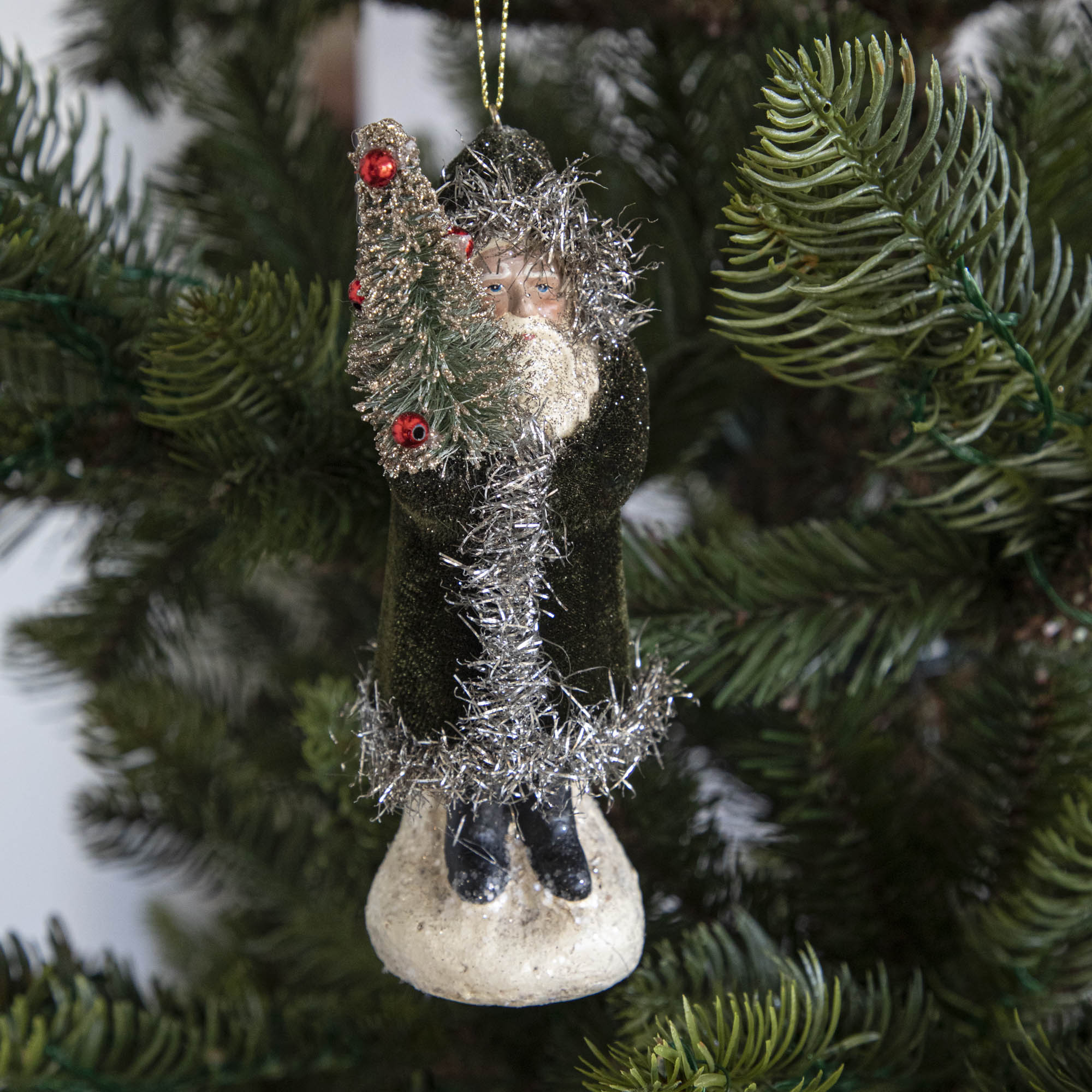 A moss green-robed Santa Claus ornament on a tree.