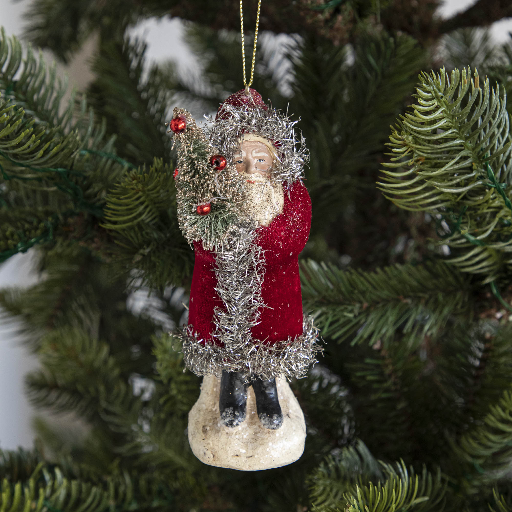 A red-robed Santa Claus ornament on a tree.