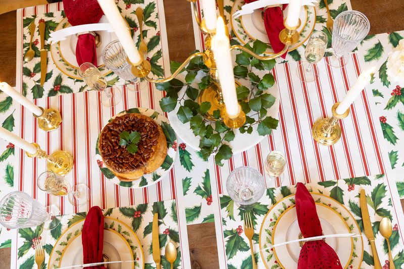 Decorative Christmas table setting with red and green patterns, candles, and gold accents.