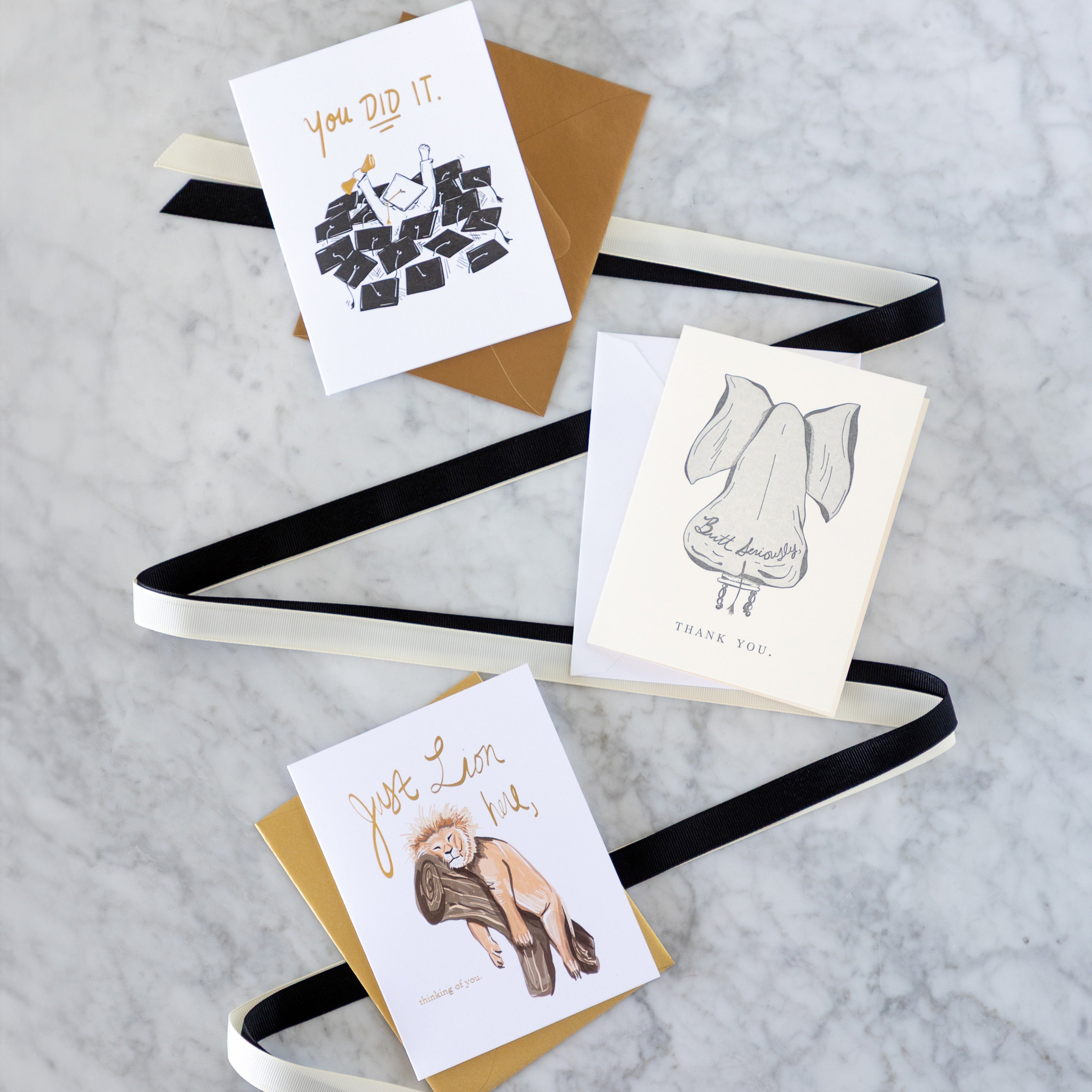 Good Juju Ink cards on a marble table with black and white ribbon in between them.