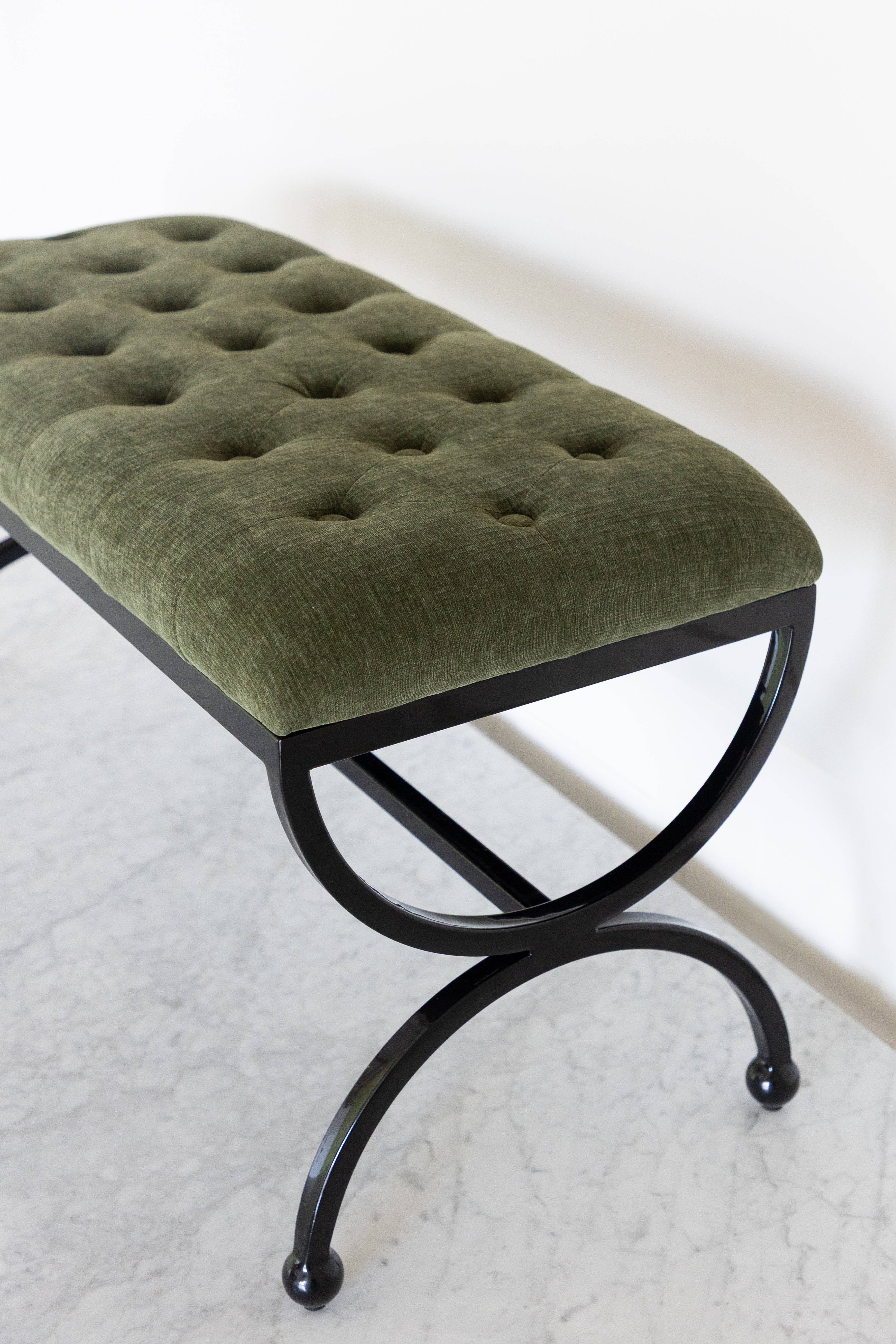 Green upholstered bench with black metal frame on a white background