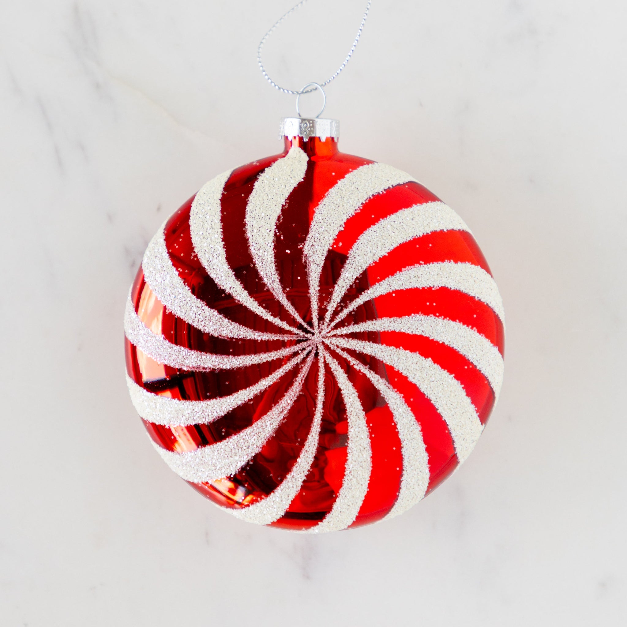 Red and white striped Christmas ornament on a marble table.