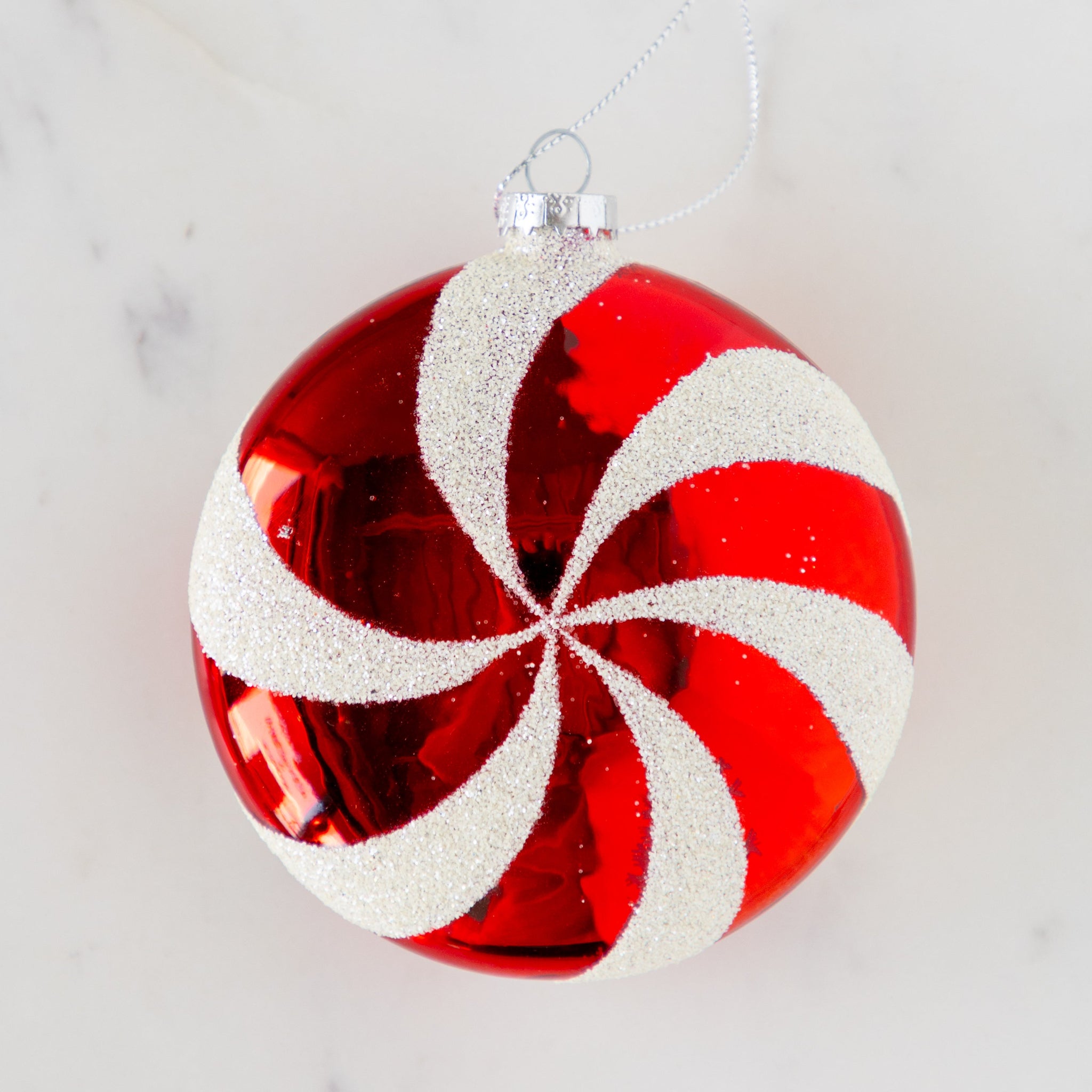 Red and white striped Christmas ornament on a marble surface.