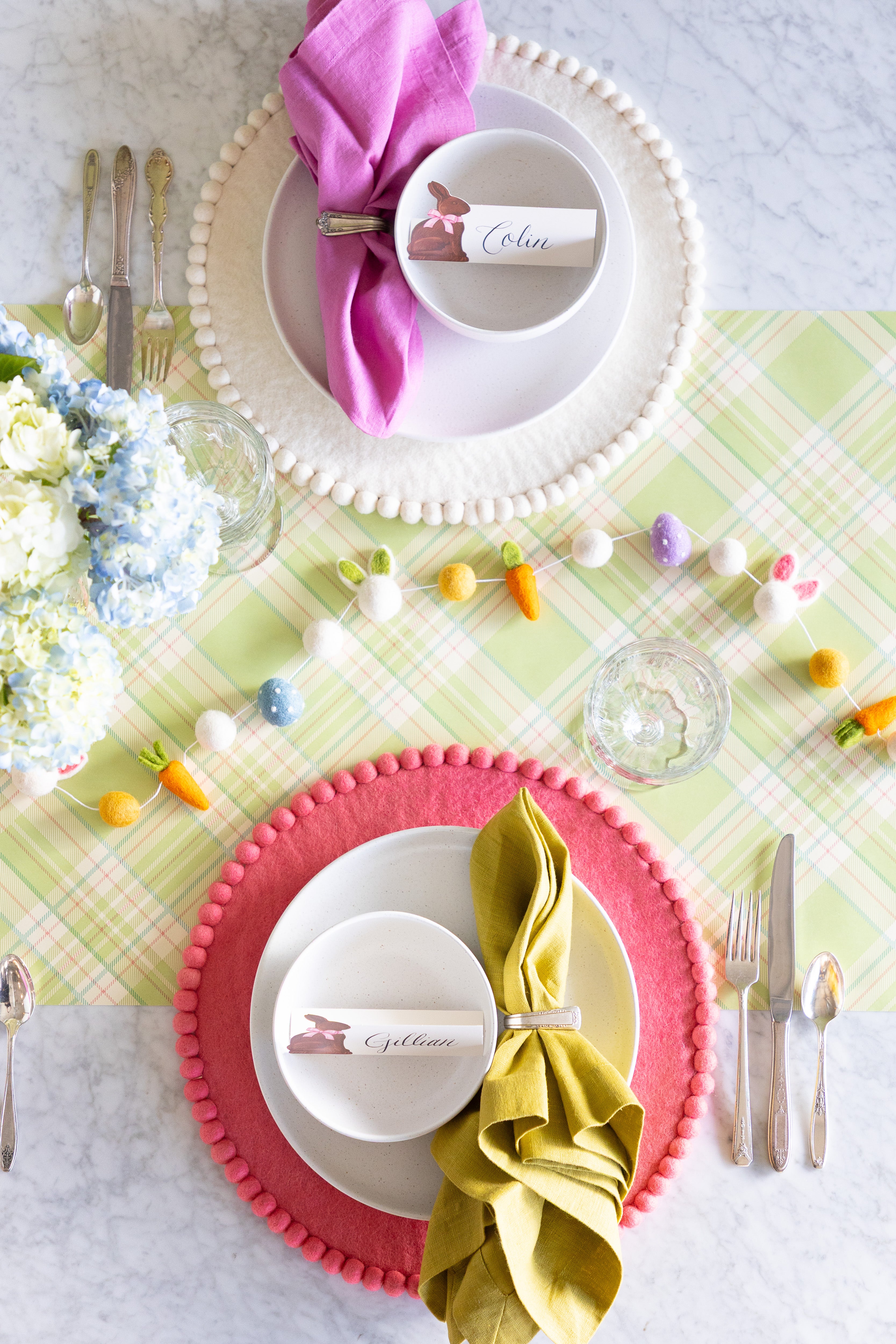 Easter-themed table setting with a floral centerpiece, Easter Felt Garland, Pink, Cornflower Blue, Spring Green and White Pom Pom Felt Placemats, and Hershey&