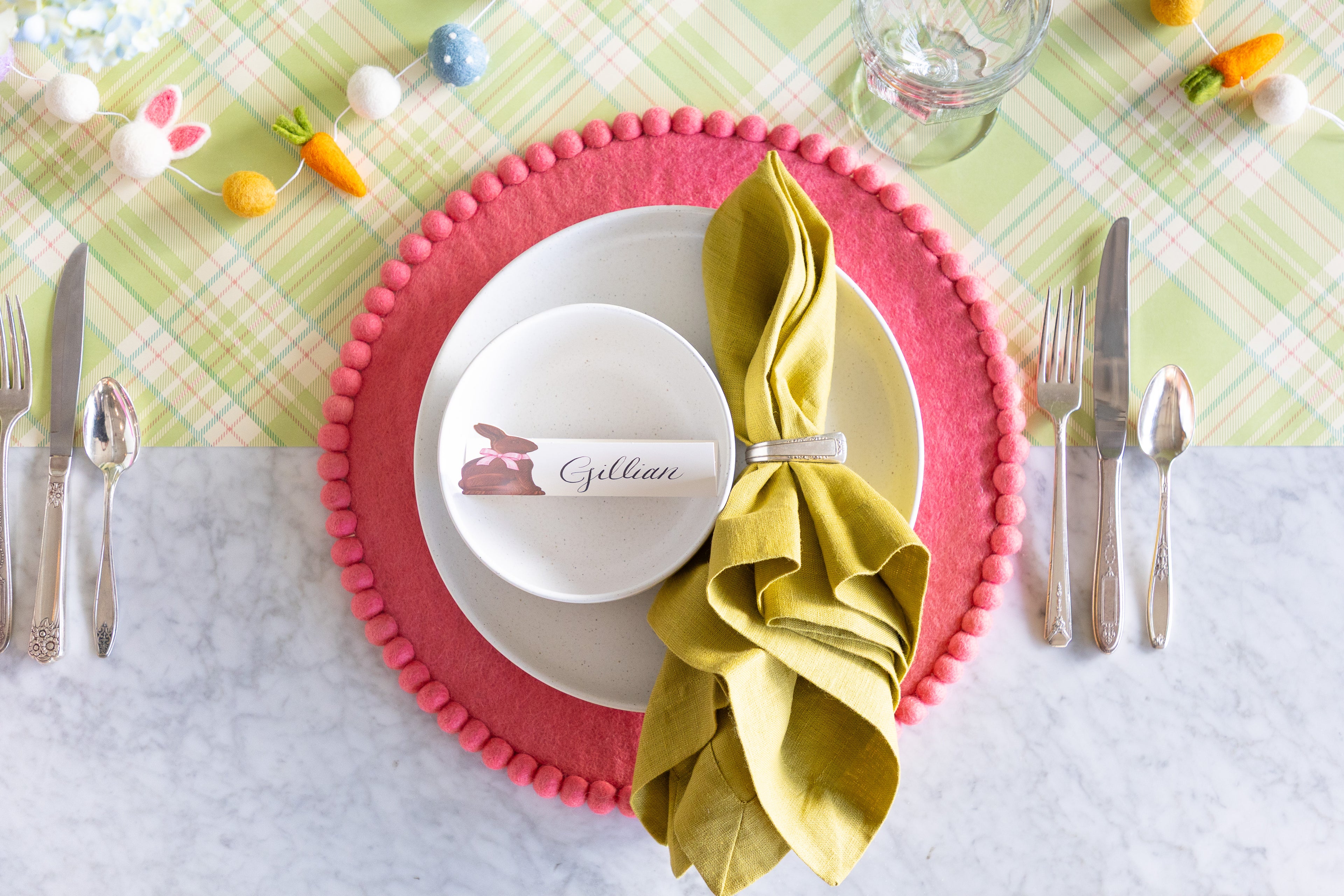Easter-themed table setting with a Pink Pom Pom Felt Placemat, white plate, Hershey&