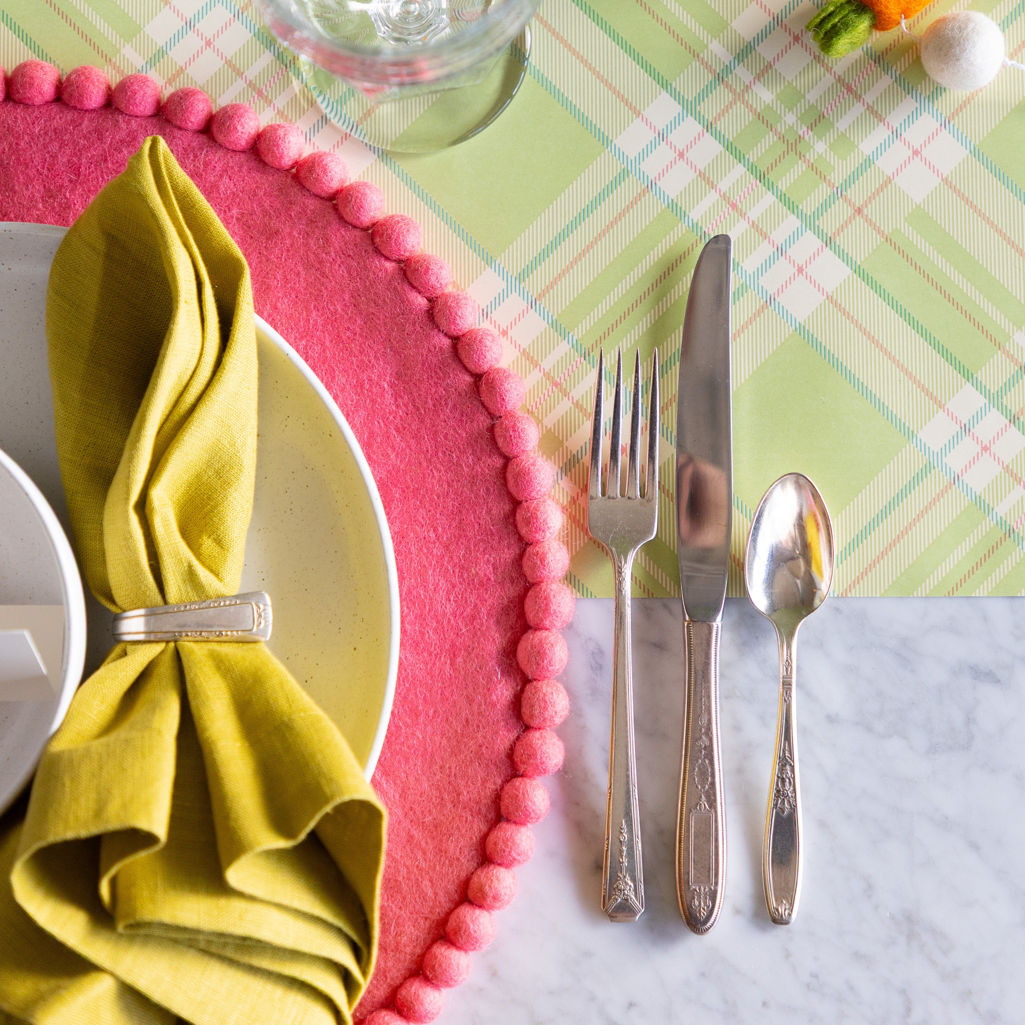 Easter-themed table setting with a Pink Pom Pom Felt Placemat and vintage silverware on the Green Plaid Runner.