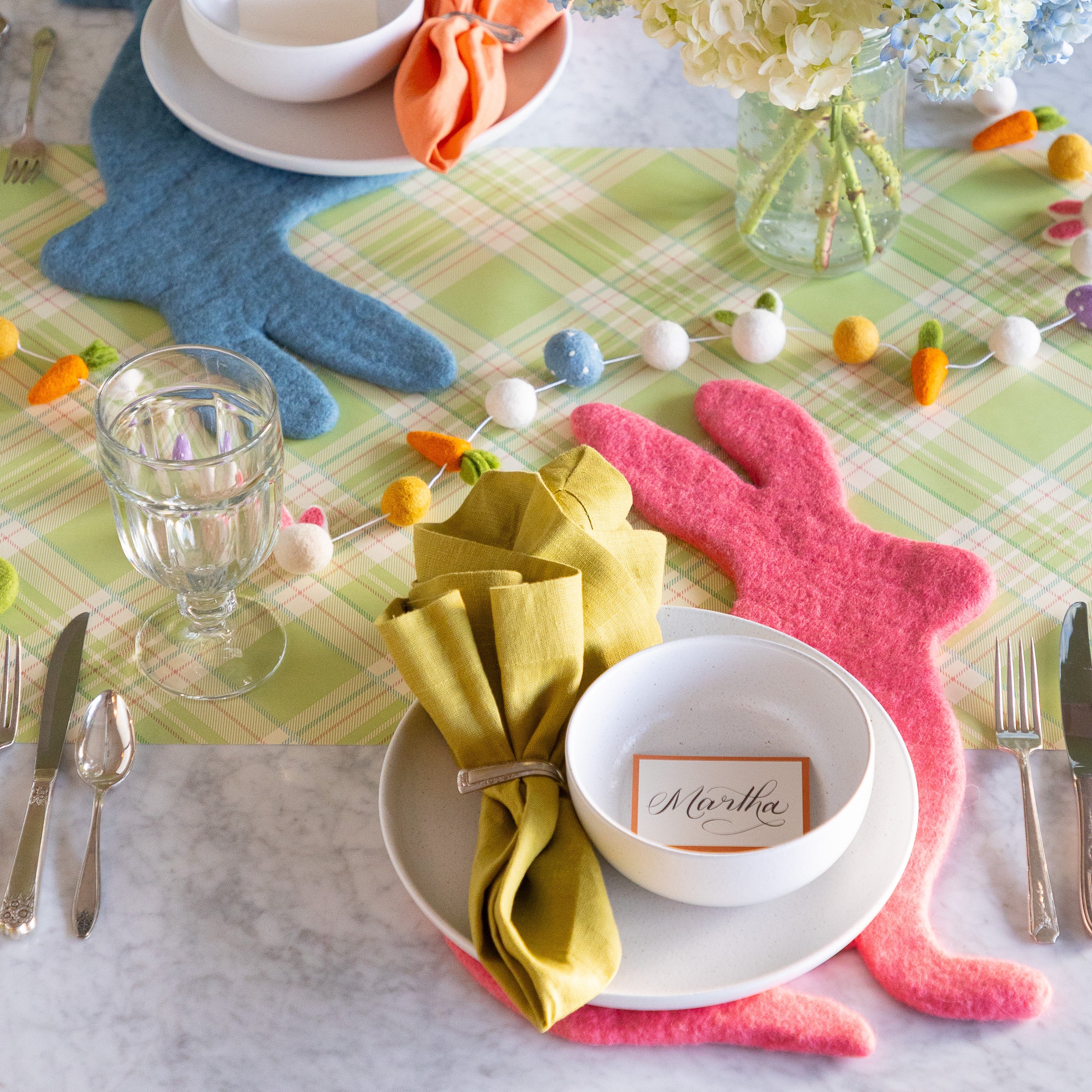 Easter table setting with the Pink Bunny Felt Placemat, white dinnerware, Easter Felt Garland and Orange Frame Place Card on the Green Plaid Runner.