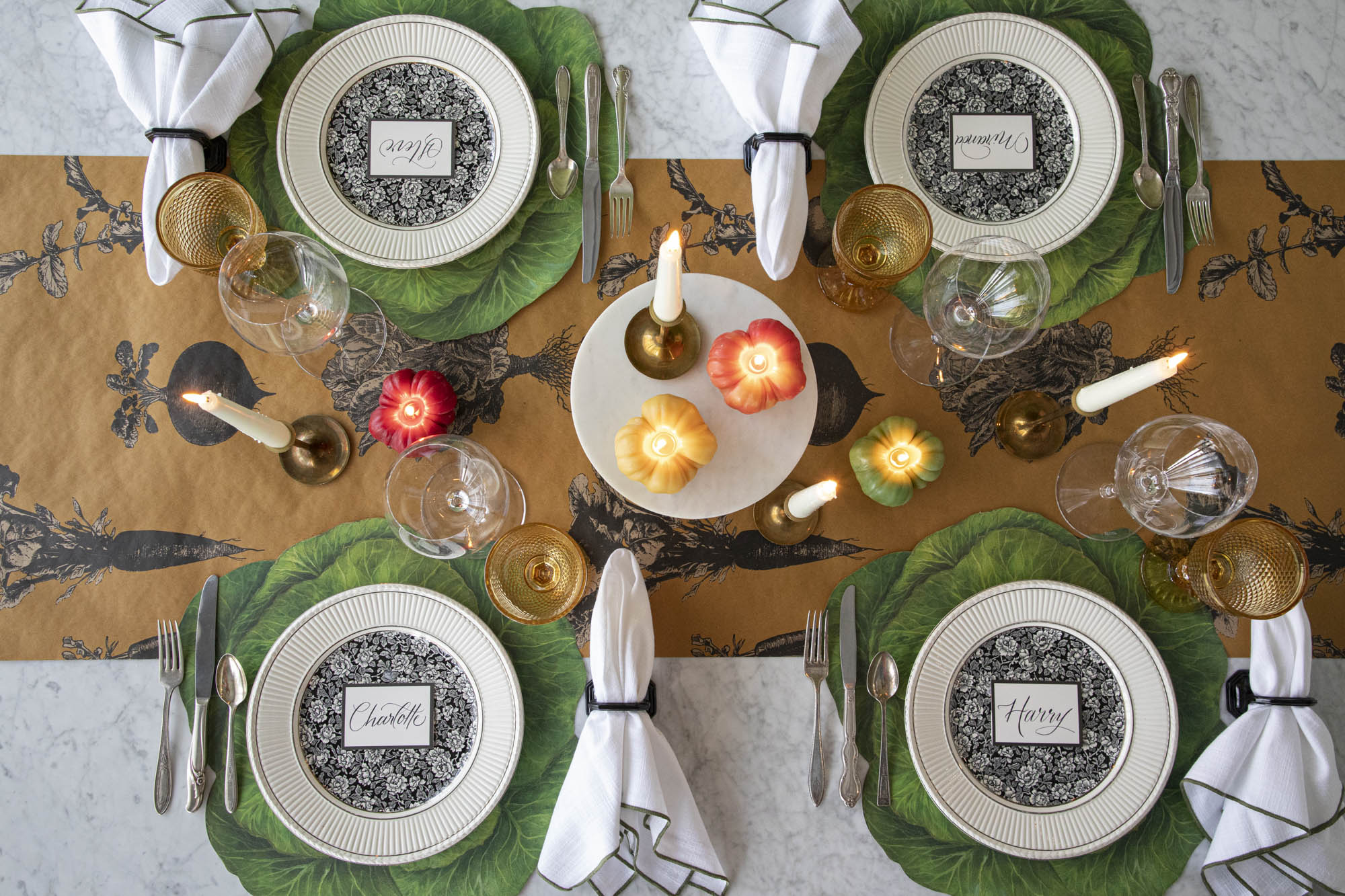 Dining table setting with decorative plates, cutlery, candles, and napkins on the Die-cut Cabbage Placemats and Farmers&