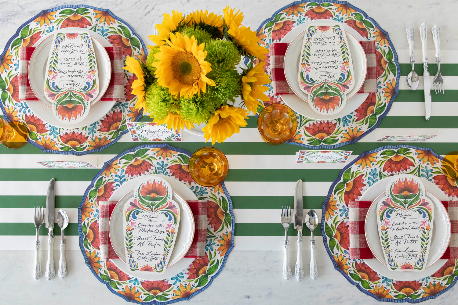 A colorful table setting for four with sunflowers, plates, and Die-cut Fiesta Floral Placemats from Hester &amp; Cook, from above.