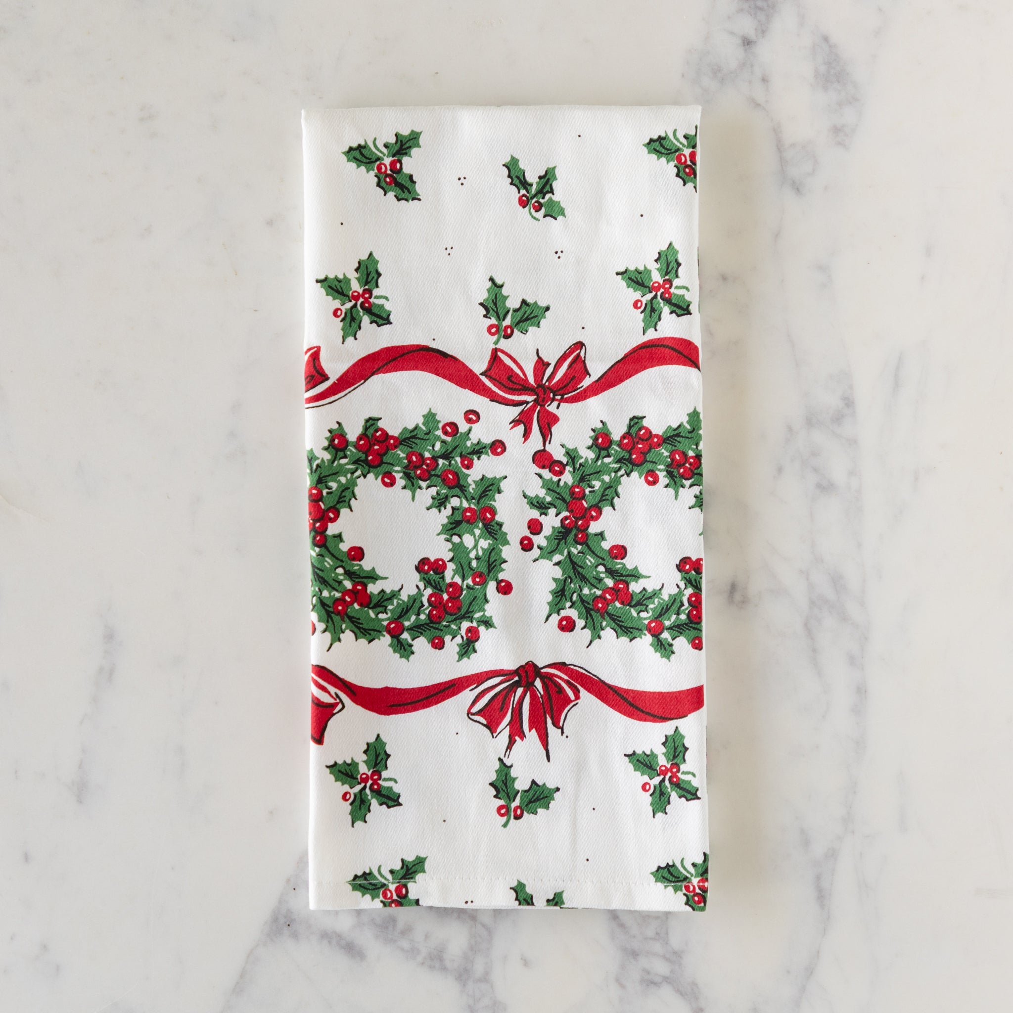 Vintage Holly Dishtowel folded, on a marble table.