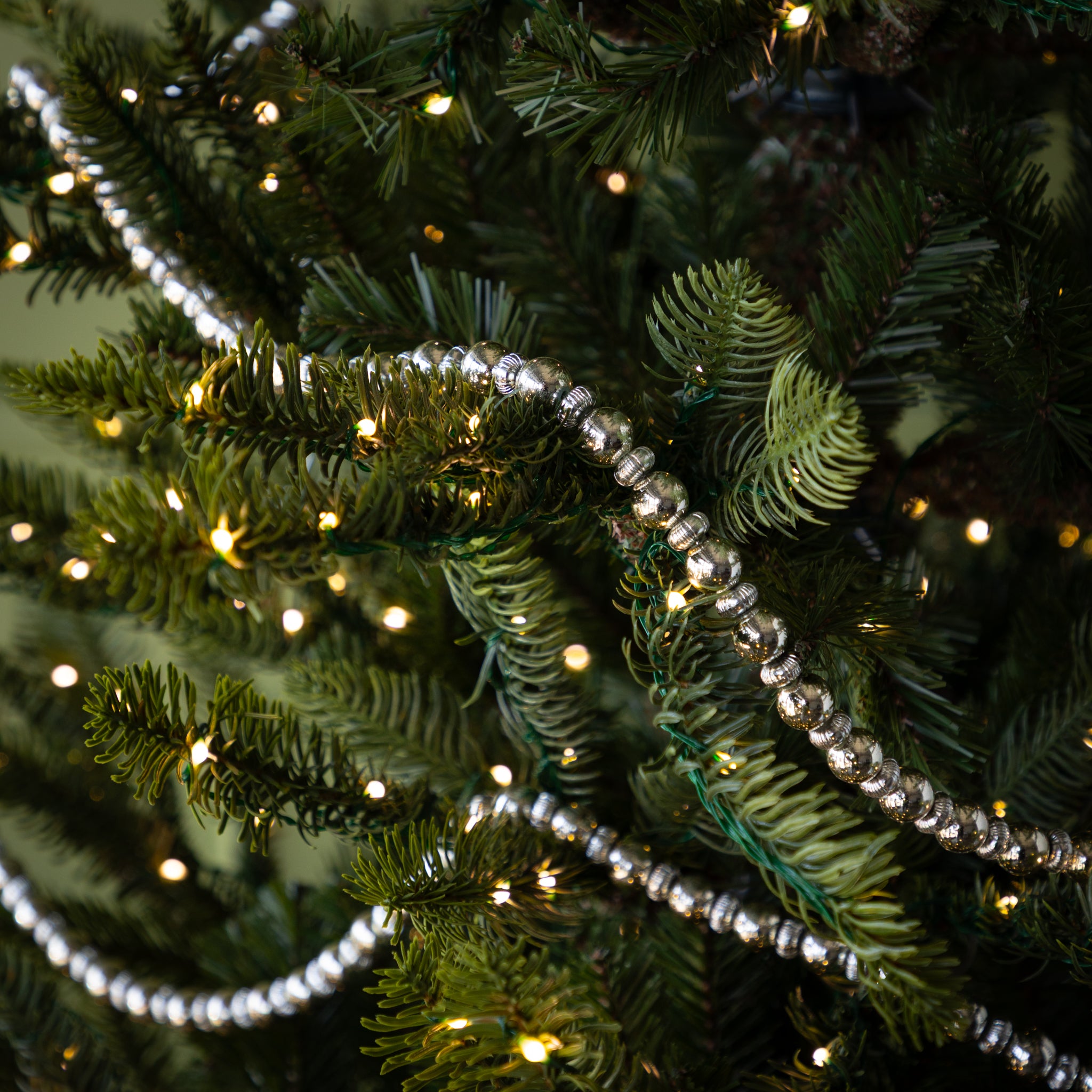 Close-up of a Christmas tree with silver tinsel and lights.