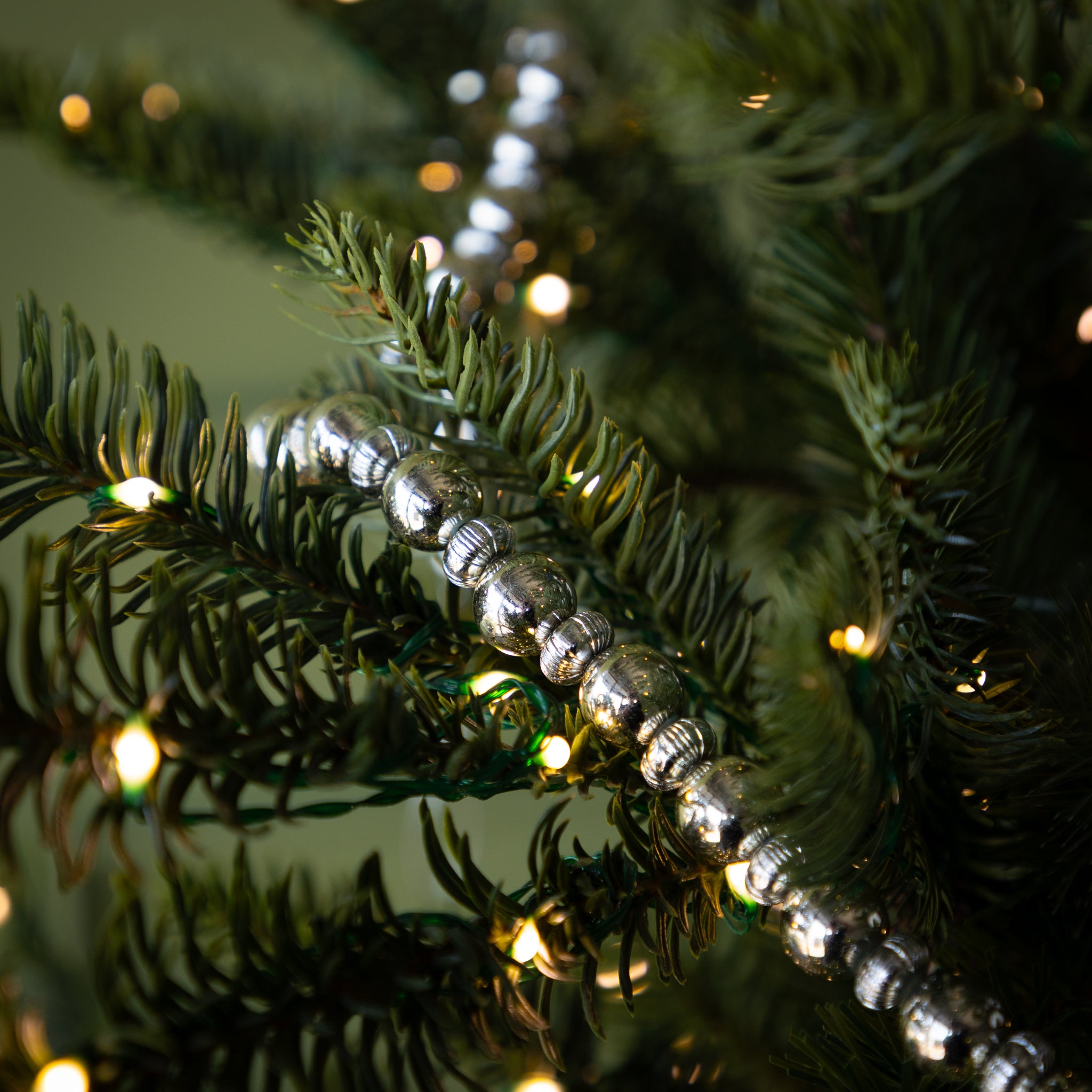 Decorative silver garland on a Christmas tree with lights.