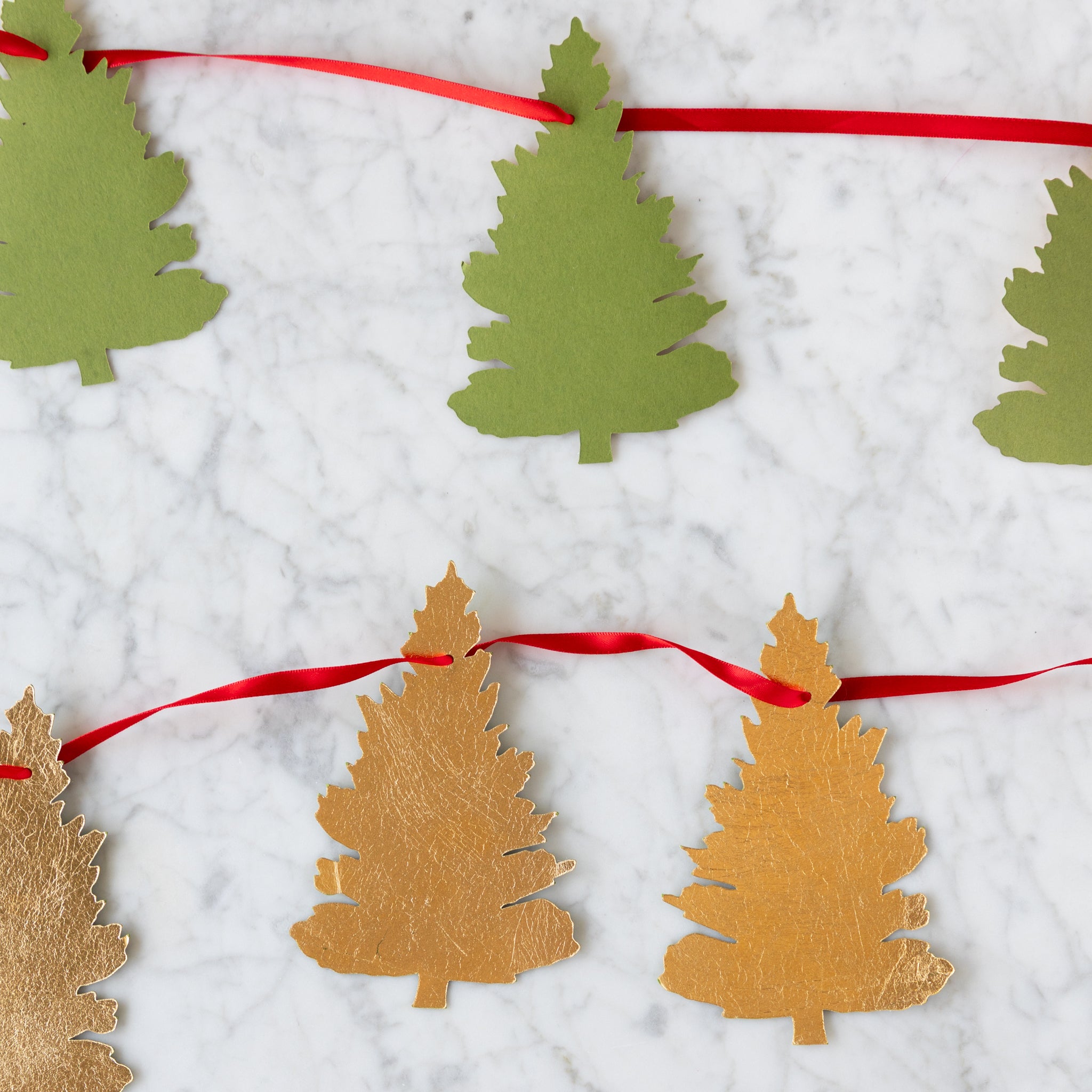 Decorative garland with green and gold tree-shaped cutouts on a white background.