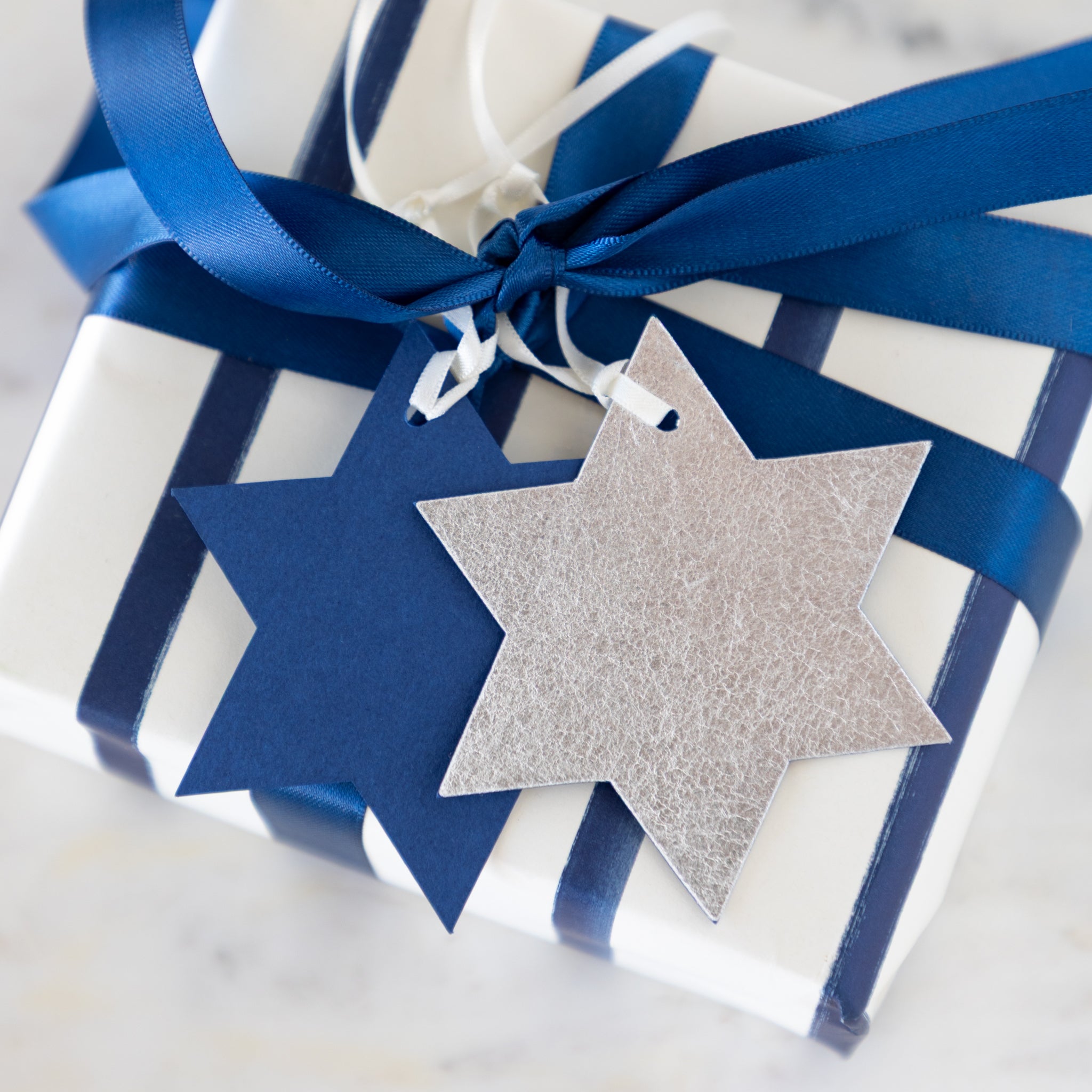 Gift wrapped in blue and white with Star of David tags on a light background.