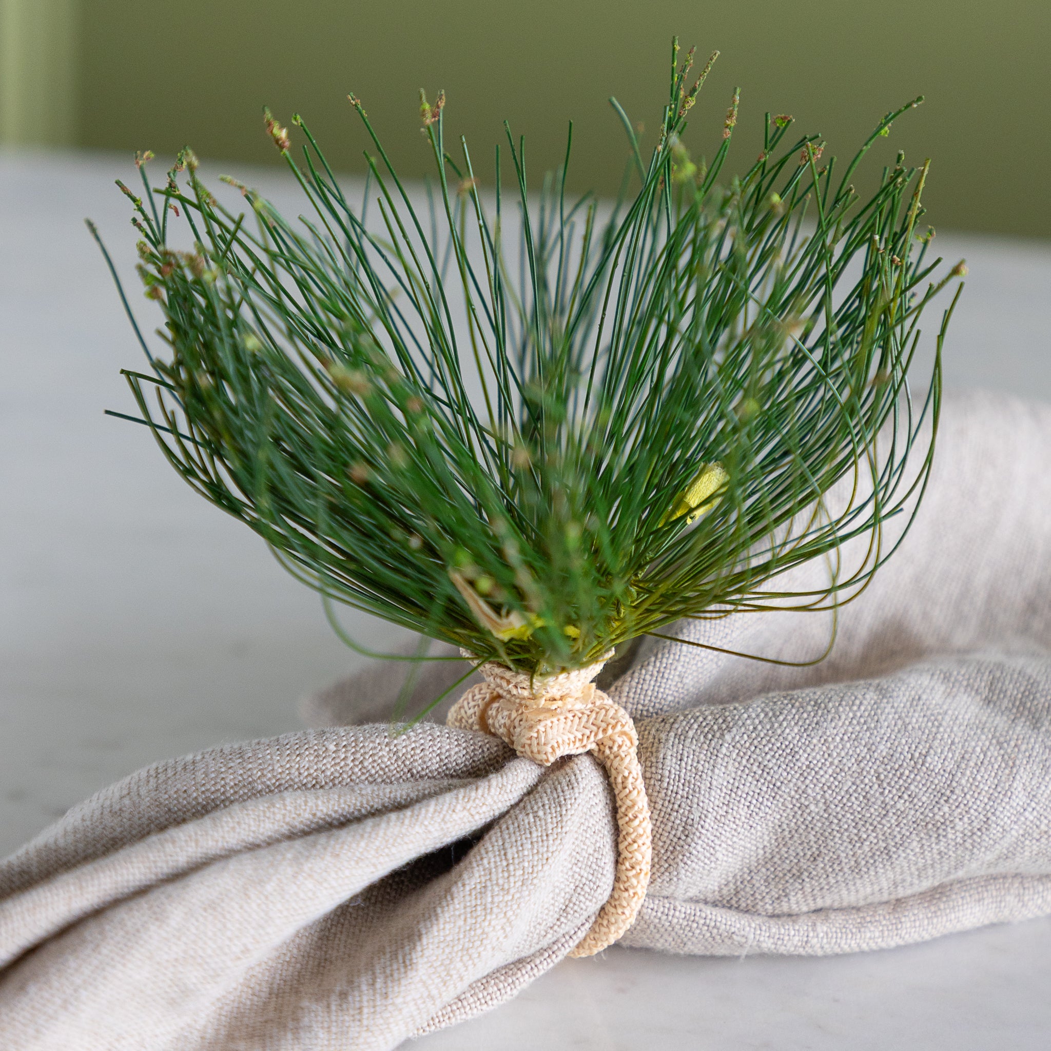 Cypress Bloom Napkin Ring with a beige napkin on a marble table.