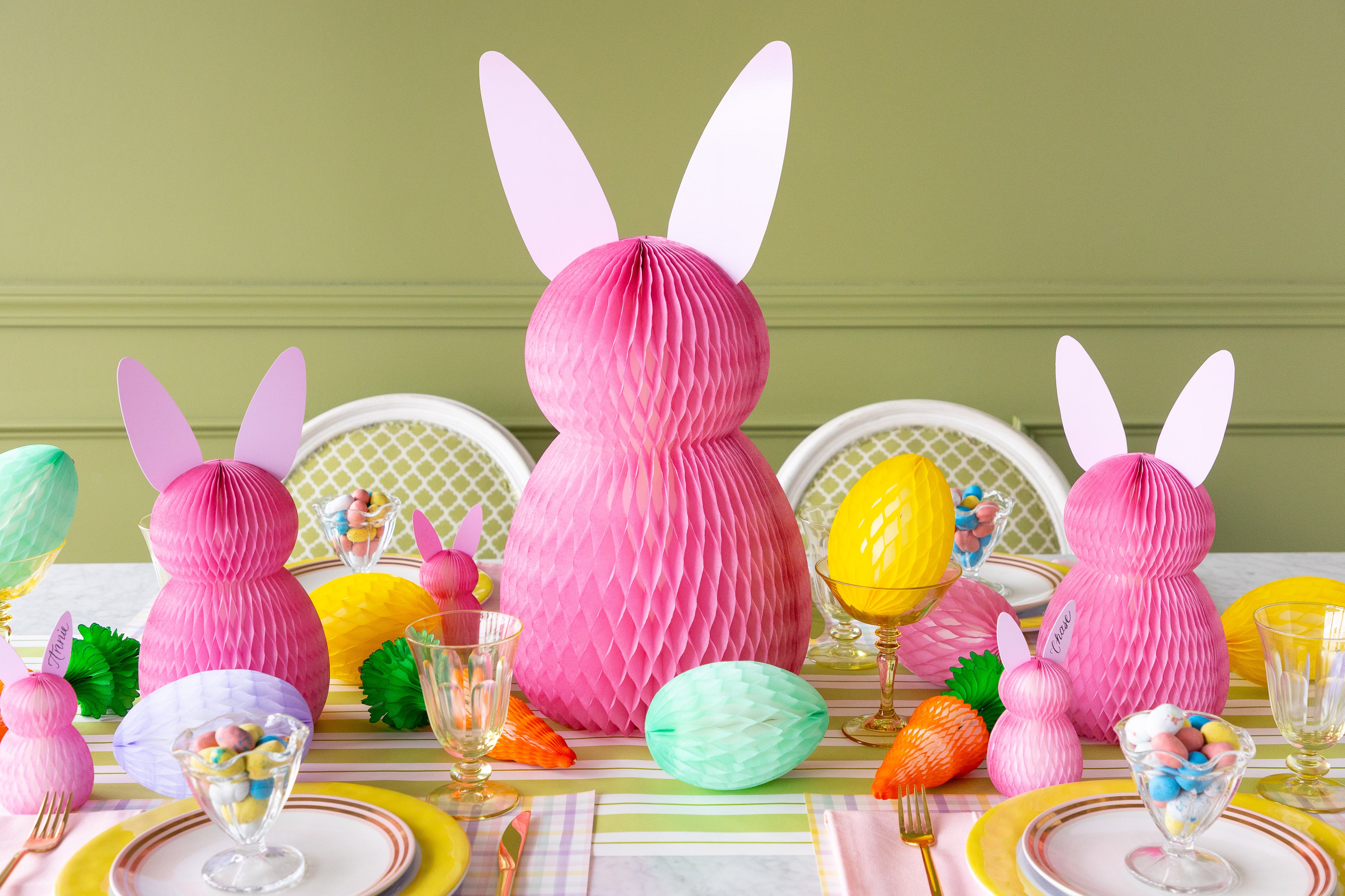 Easter-themed table setting with pink bunny decorations and colorful eggs on a green background.