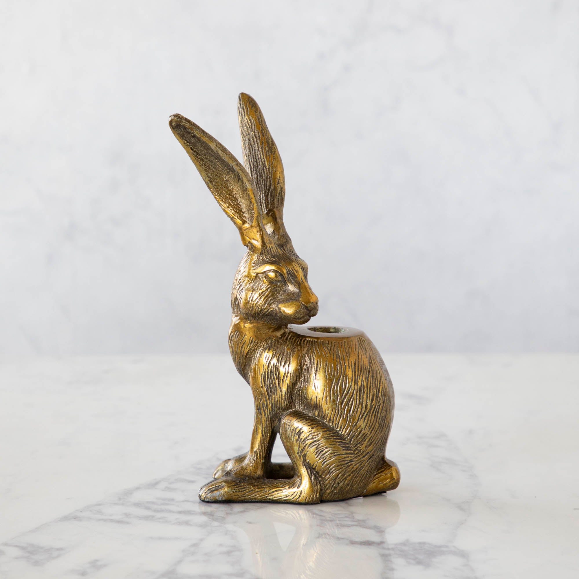 Halcyon Seated Hare Taper Candleholder looking back with a hole in its body for a taper candle.