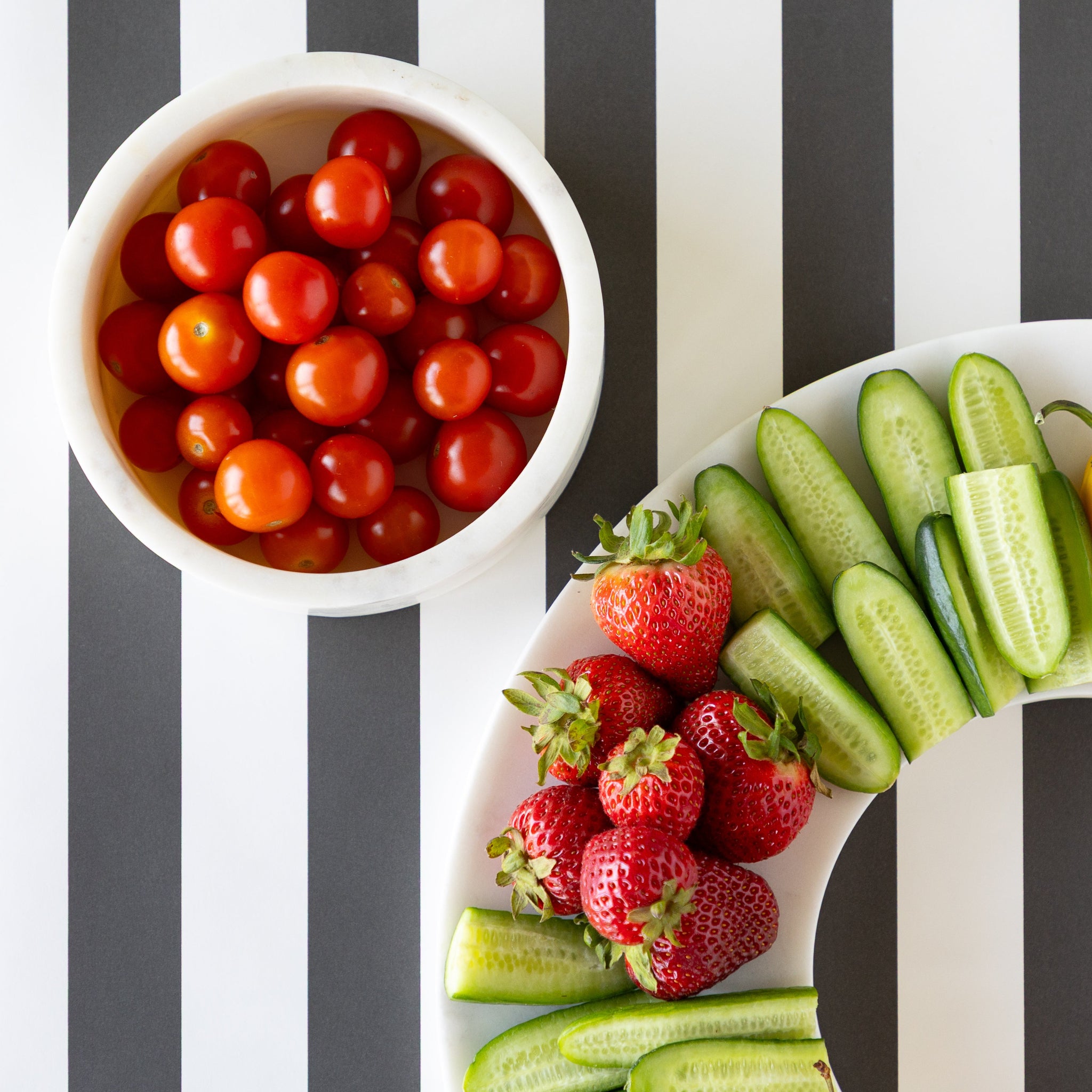 The Marble Chip and Dip Server bowl filled with cherry tomatoes next to assorted fruit and veggies on the platter.