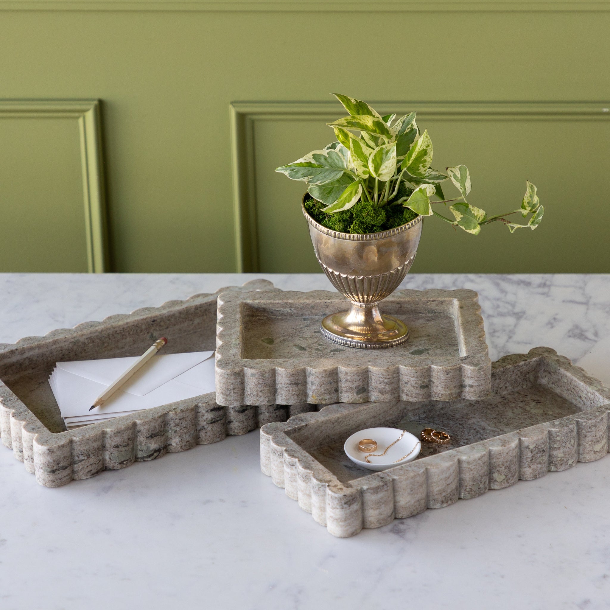 Intricate Scallop Marble Trays in 3 sizes with a potted plant in the small, trinket dish with jewelry in the medium and envelopes and a pencil in the large.