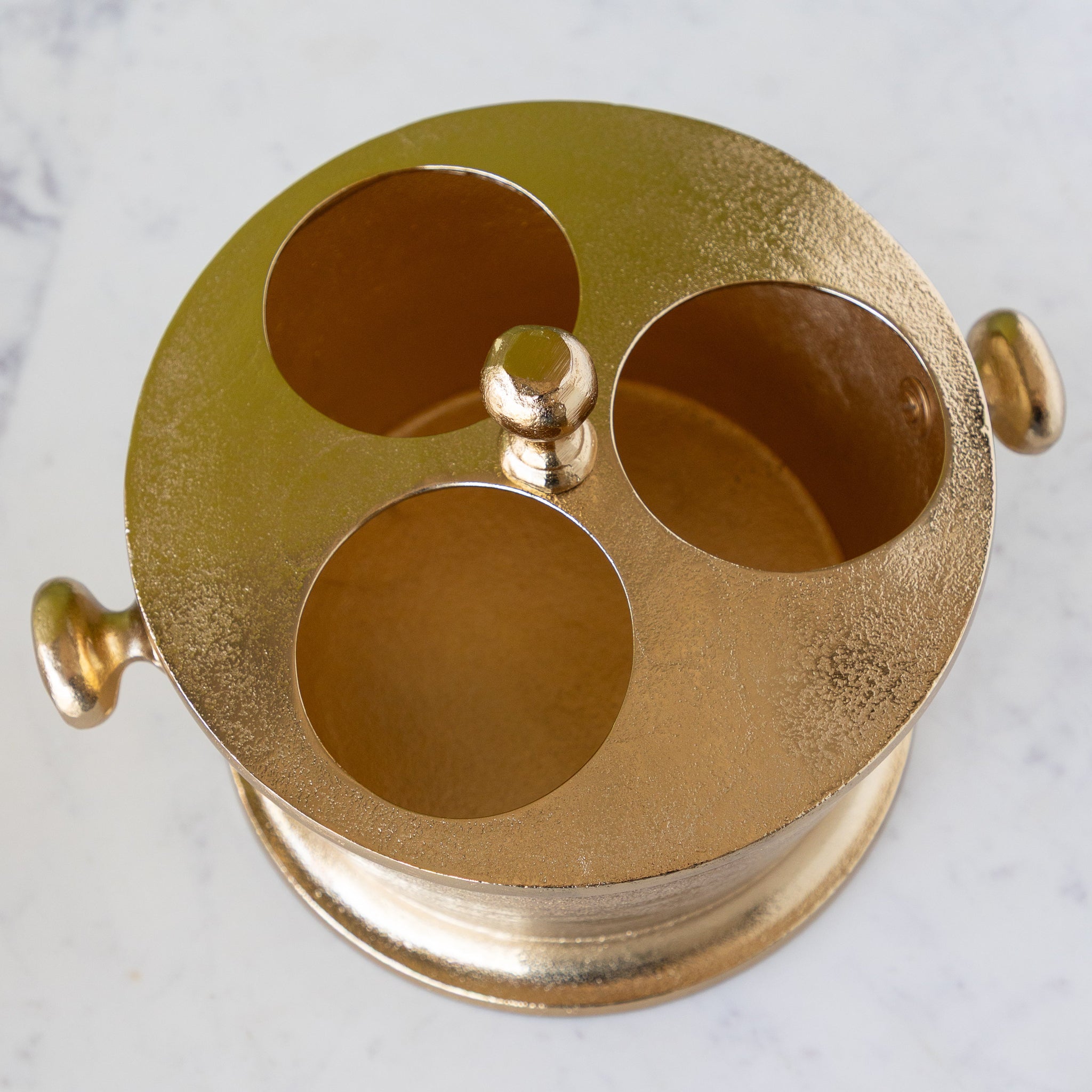 Gold Raw Aluminum Bottle Holder with 3 circular holes for wine bottles, a knob in the center and on both sides of the bucket.