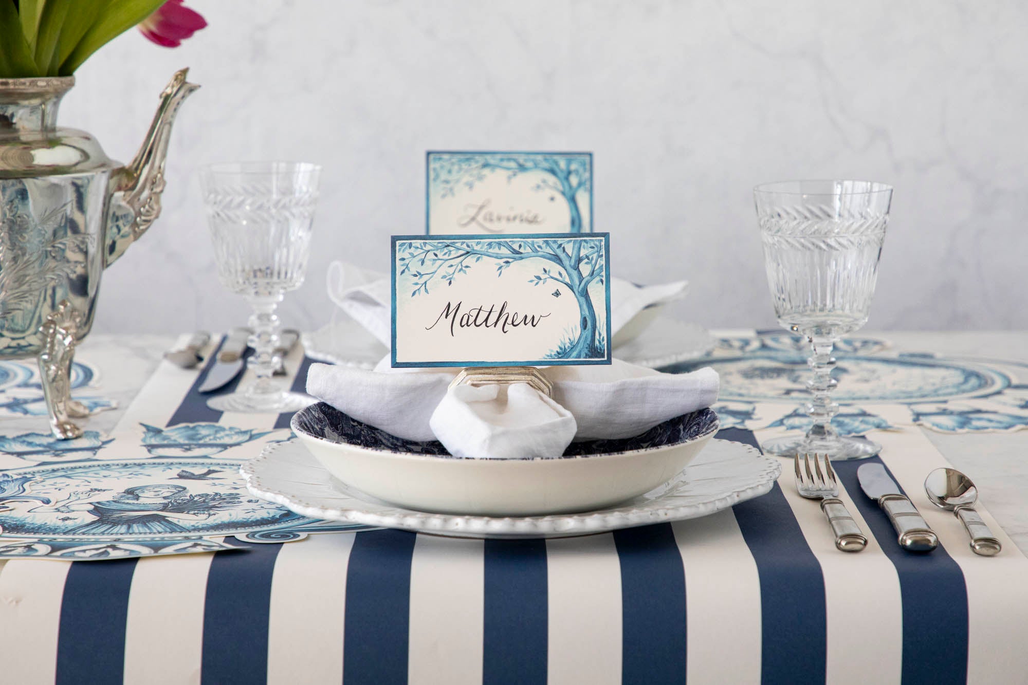 A serene Indigo Meadow place card at a table set with plates and glasses, making guests feel extra special. (Brand: Hester & Cook)
