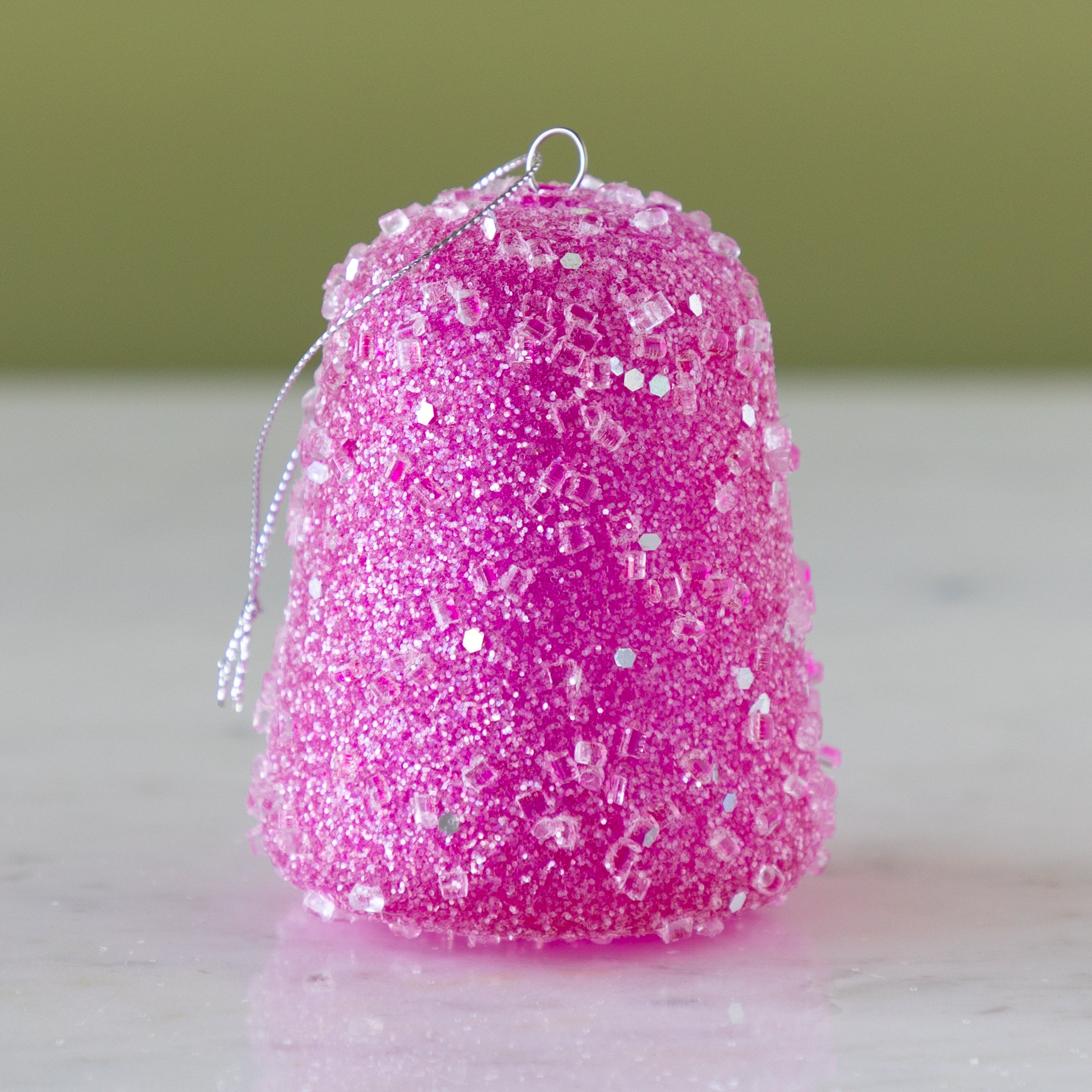 Pink glittery gum drop ornament on a neutral background.