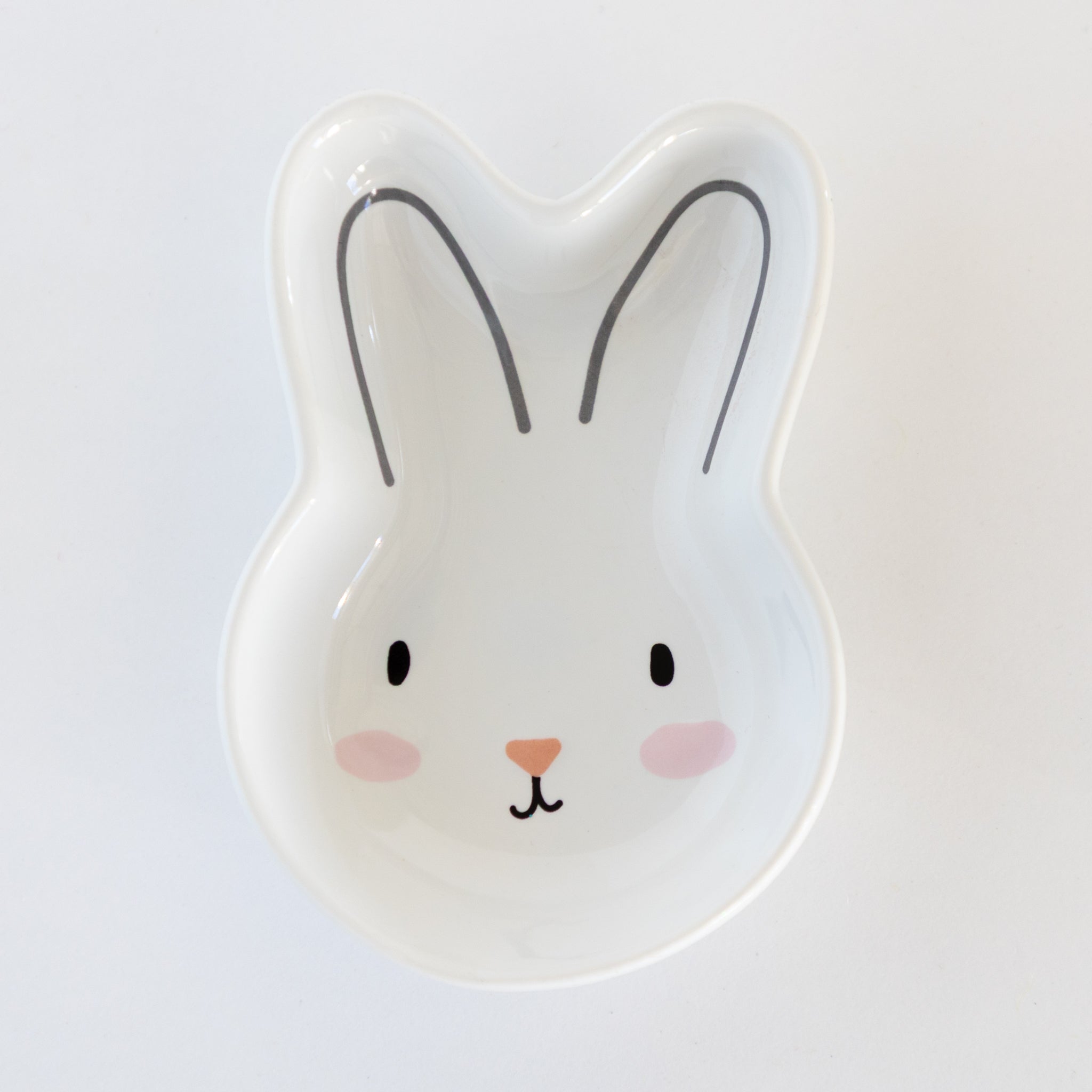 White, ceramic rabbit-shaped dish with a cute face on a white background.