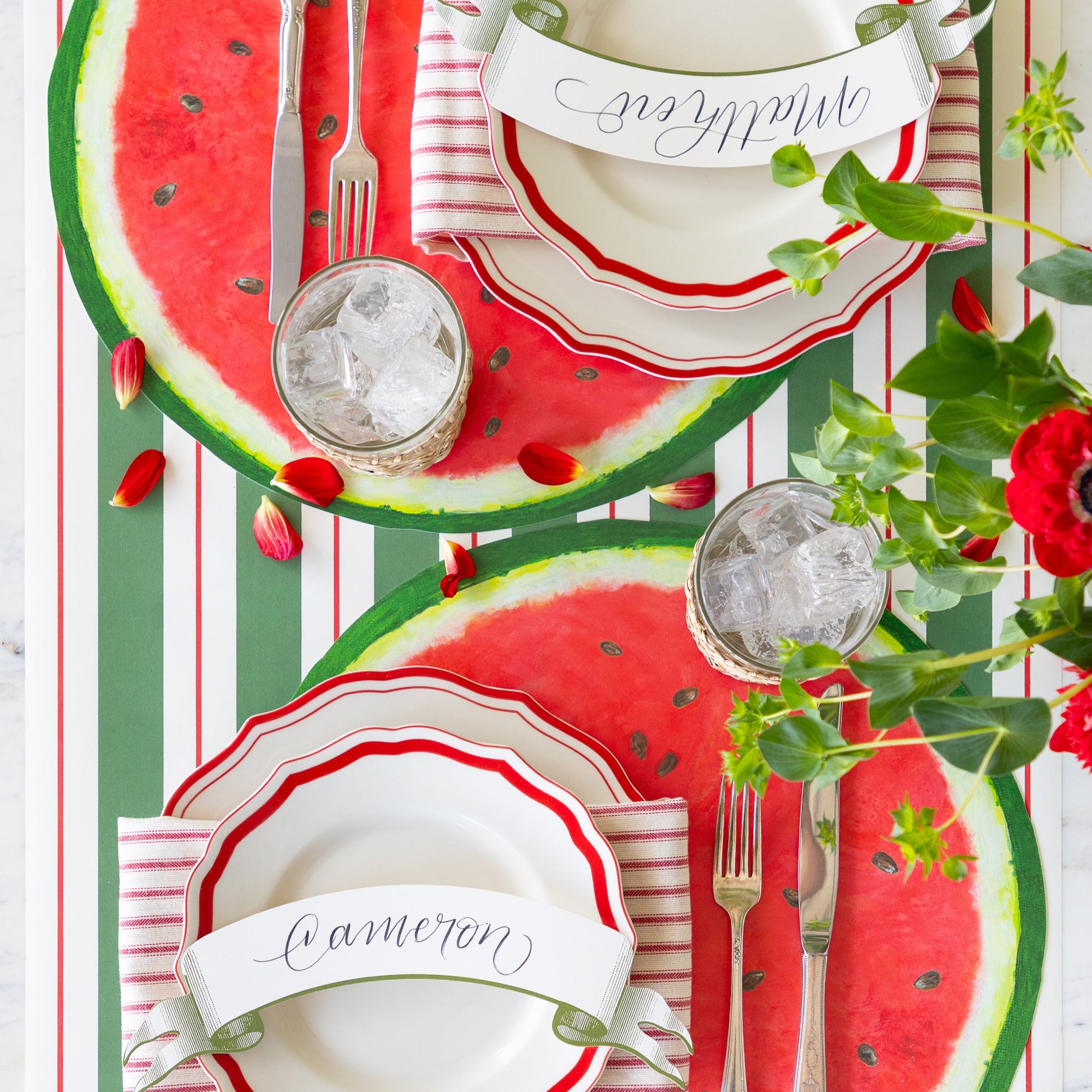 Place setting with the Die-cut Watermelon Placemat, Fancy Red Scalloped Plates, Classic Moss Banner Table Accent and silverware on the Green & Red Awning Stripe Runner.