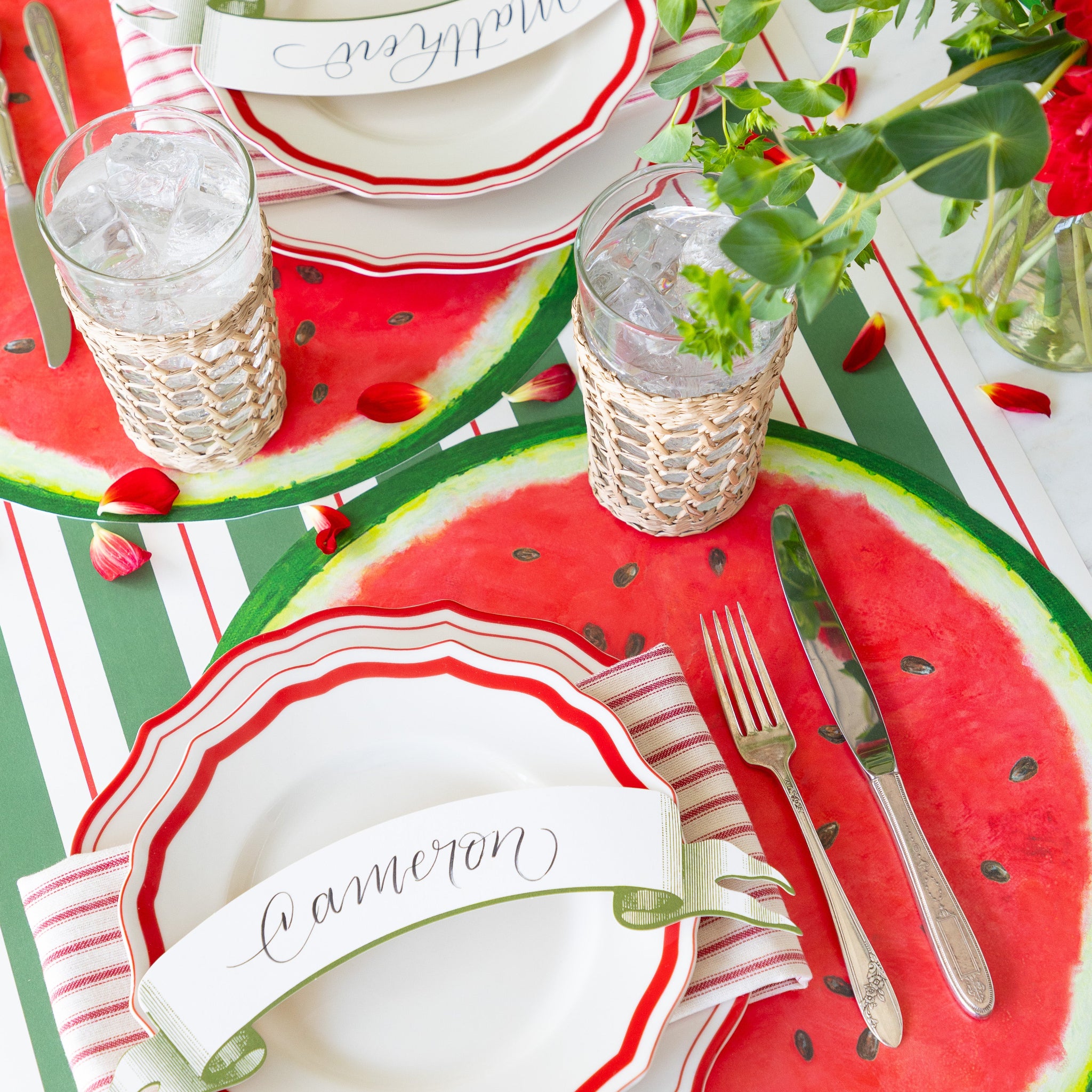 Place setting with the Die-cut Watermelon Placemat, Fancy Red Scalloped Plates, Classic Moss Banner Table Accent and silverware on the Green & Red Awning Stripe Runner.
