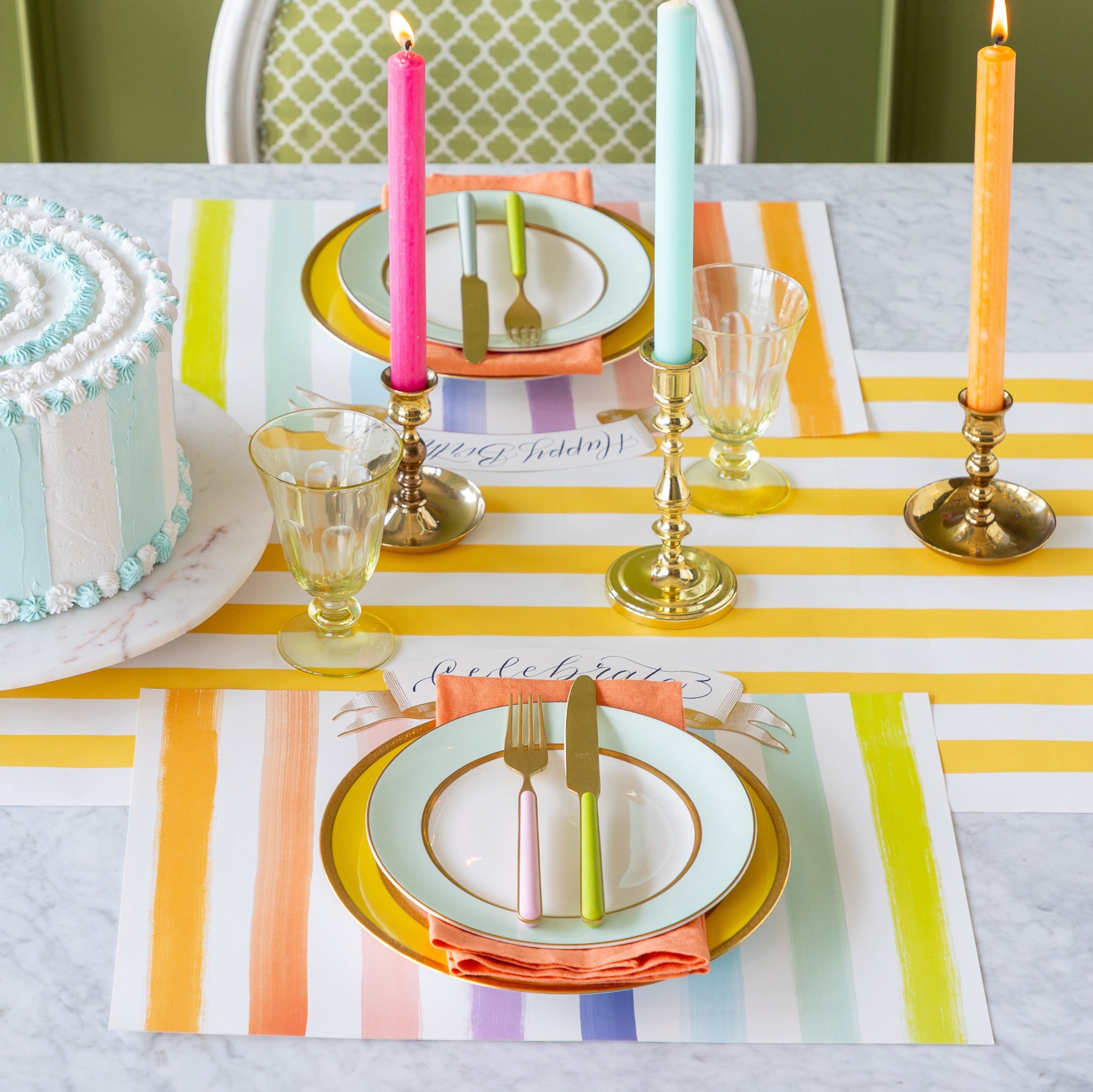 Table setting with a cake, Sorbet Painted Stripe Placemats, colorful candles and and dinnerware on the Marigold Classic Stripe Runner.