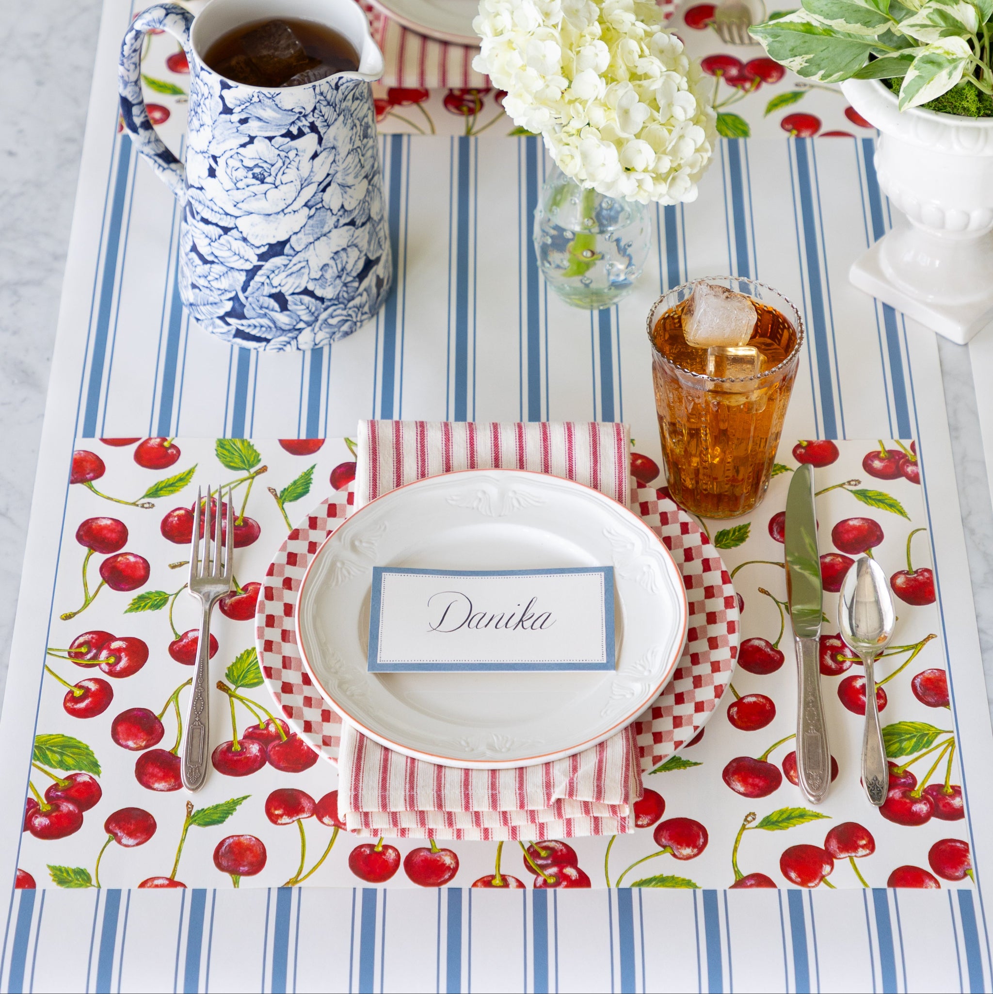 Table setting with the Cherries Placemat, Cornflower Blue Place Card, vintage dinnerware, and floral decorations on the Cornflower Blue Linen Stripe Runner.