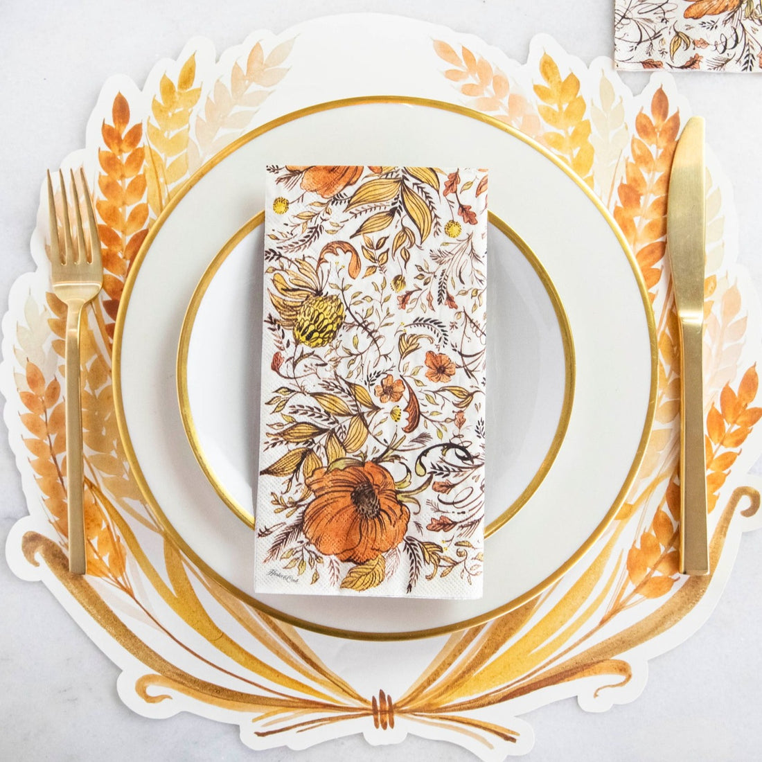 A Hester &amp; Cook Die-cut Golden Harvest Placemat featuring a gold-rimmed plate, gold knife and fork, and corresponding napkin.