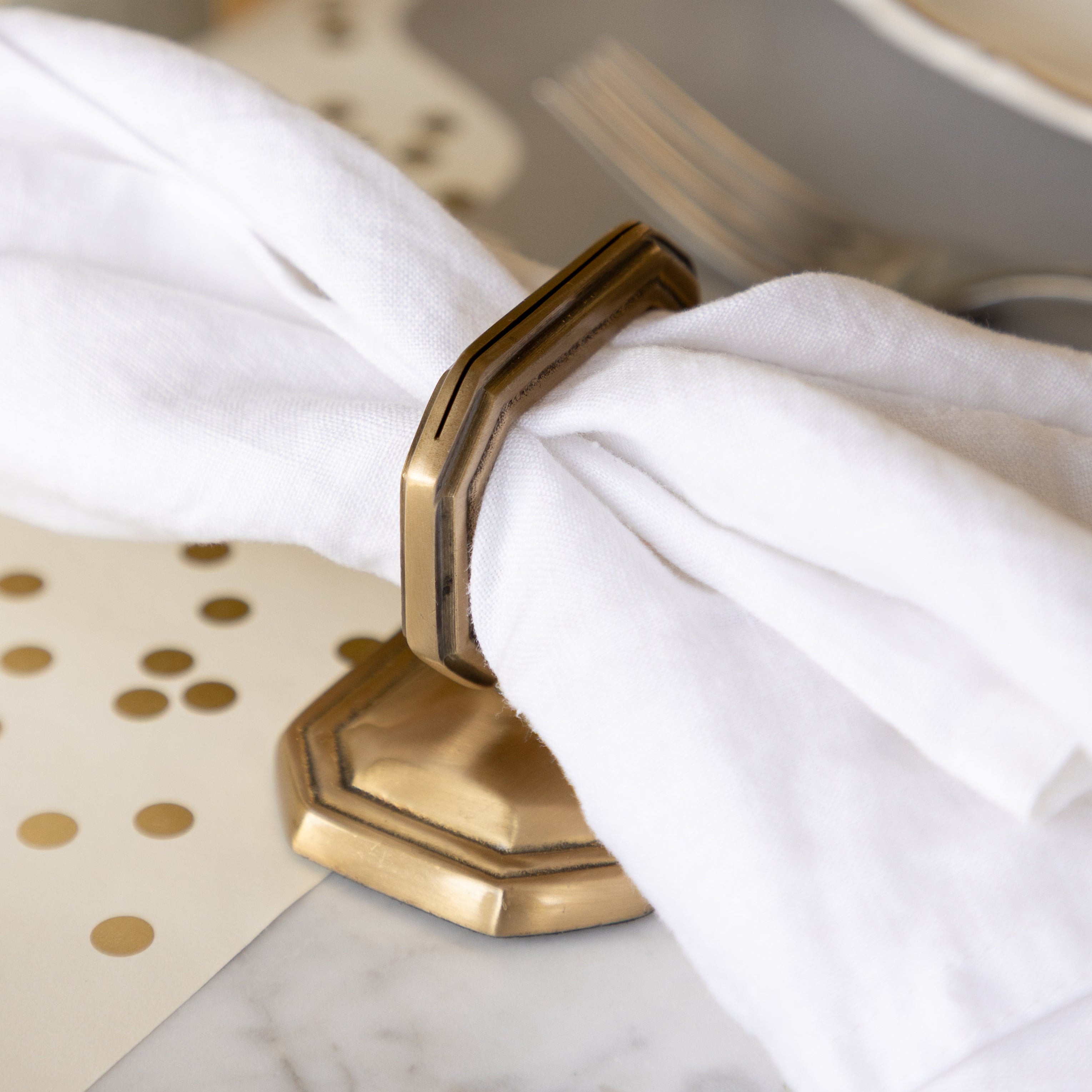 The Brass Napkin Ring with Place Card Holder with a white napkin in it.