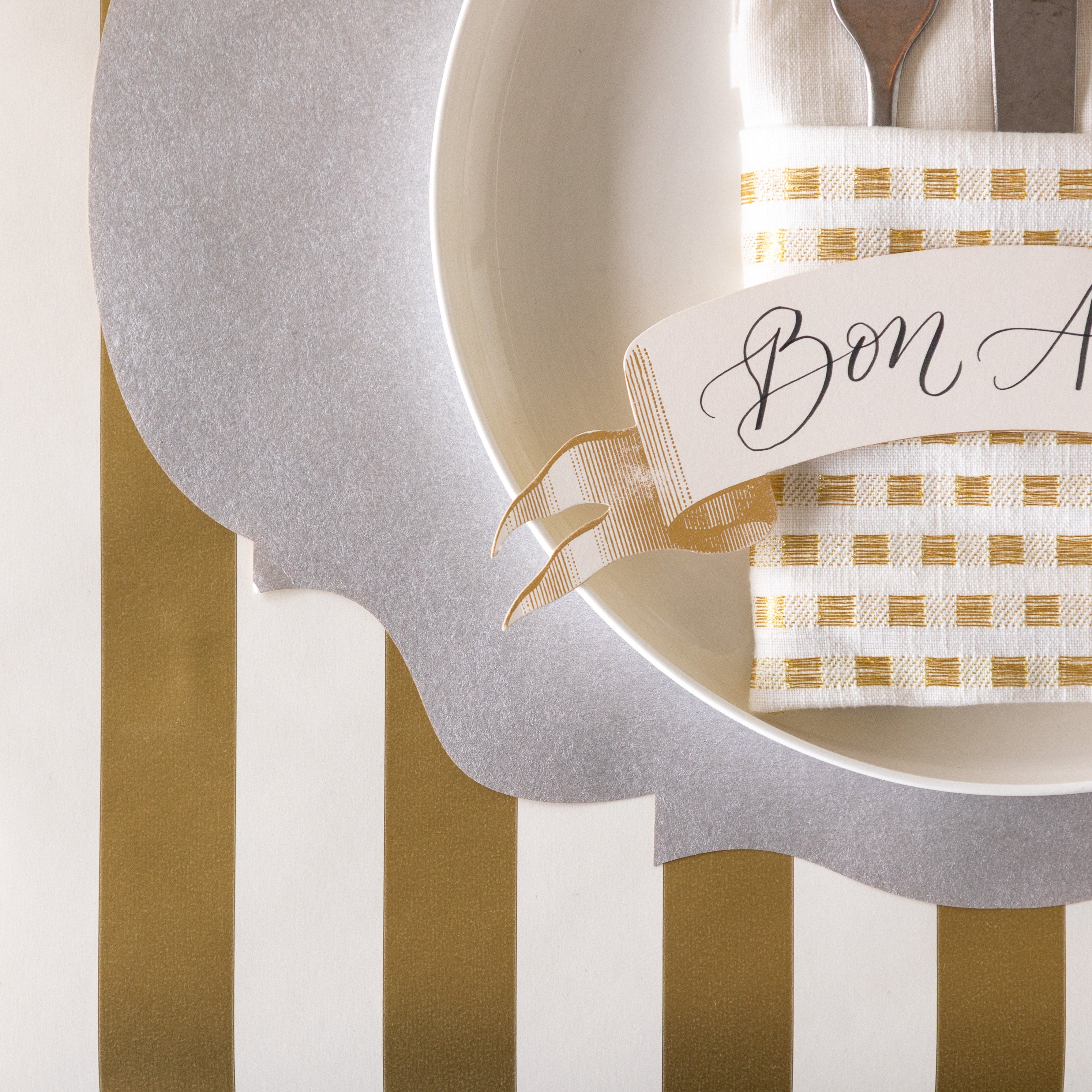 A place setting with the Die-cut Silver French Frame Placemat on the Gold Classic Stripe Runner.