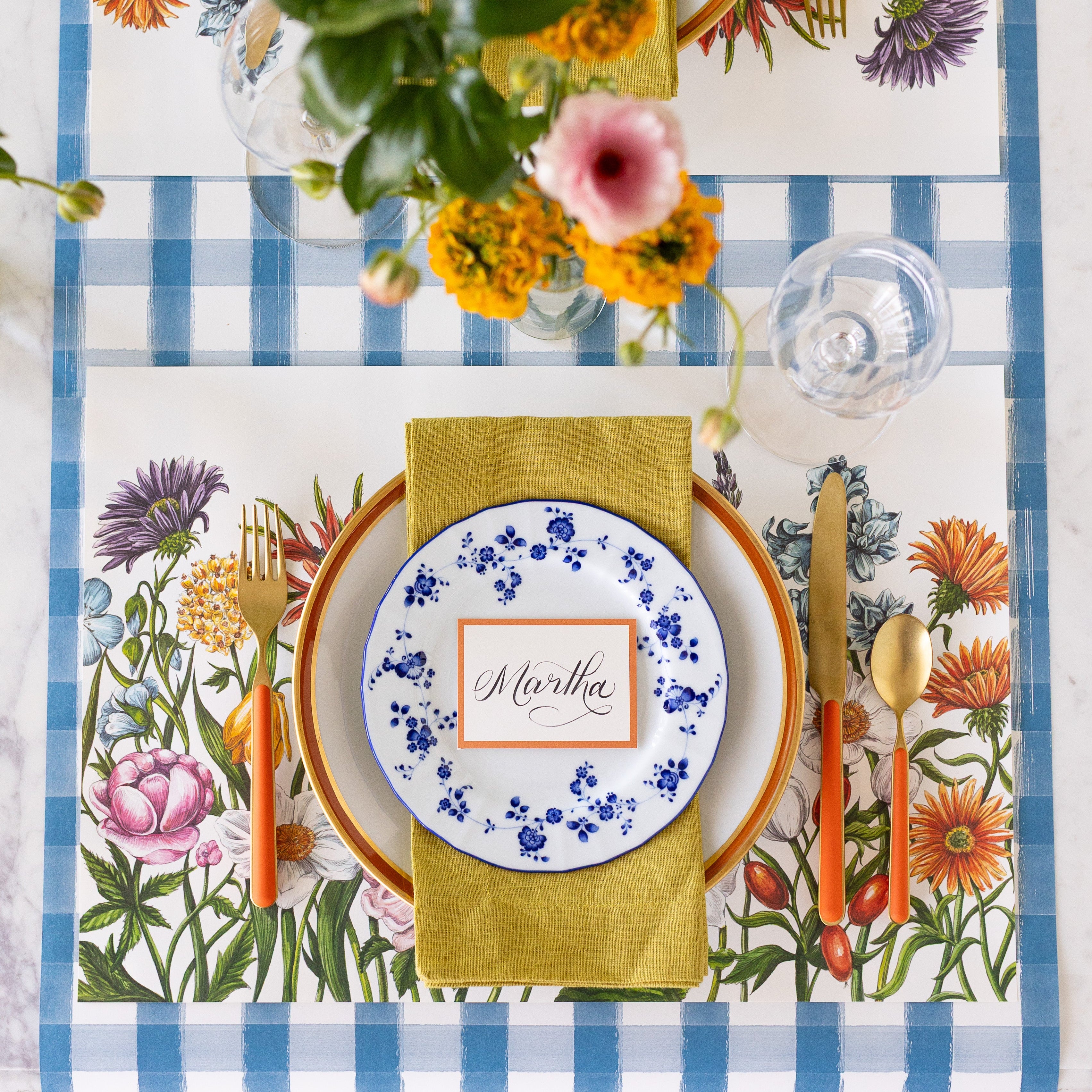 A spring table setting with the Wildflower Meadow Placemat under an elegant place setting and Blue Painted Check Runner underneath.
