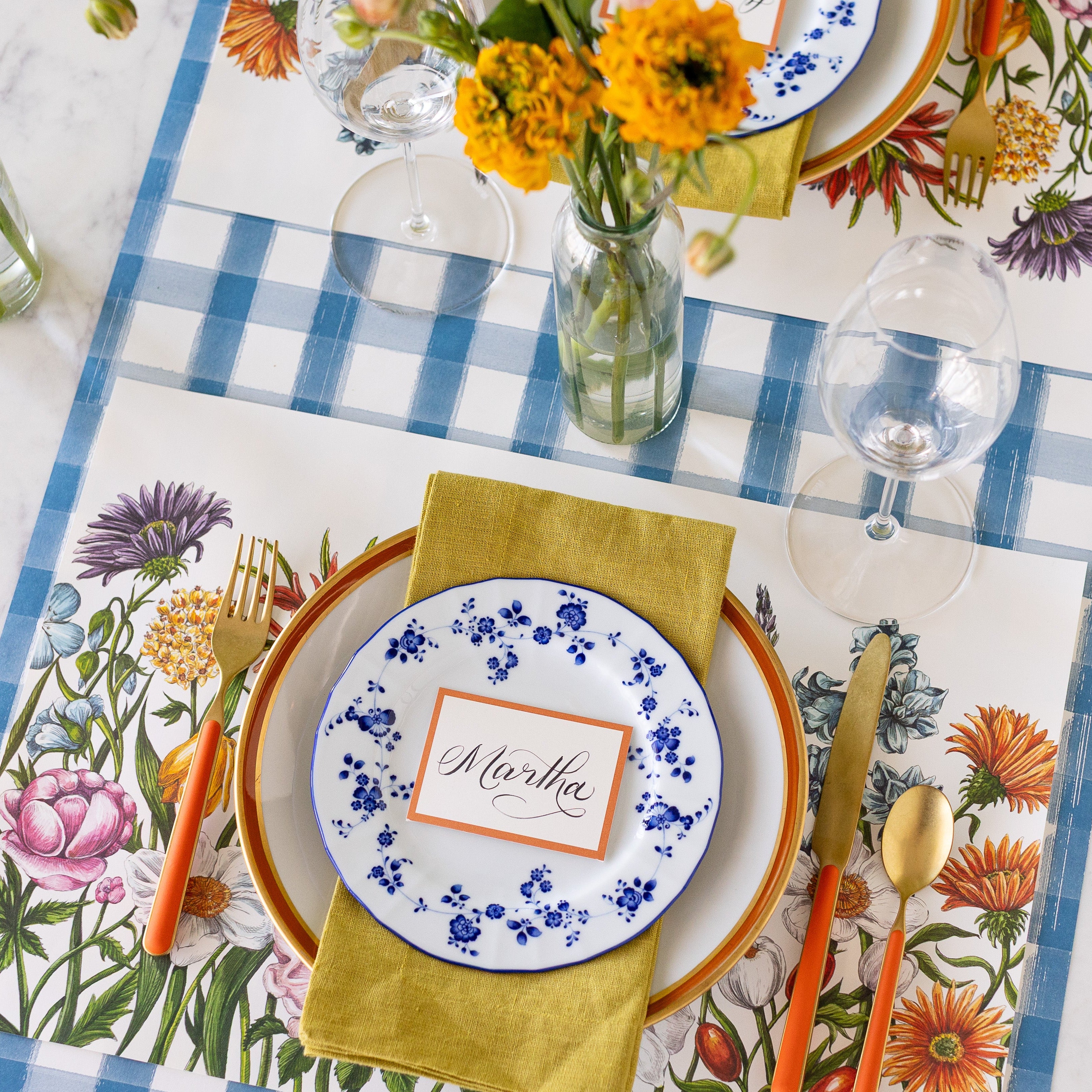 A spring table setting with the Wildflower Meadow Placemat under an elegant place setting and Blue Painted Check Runner underneath.