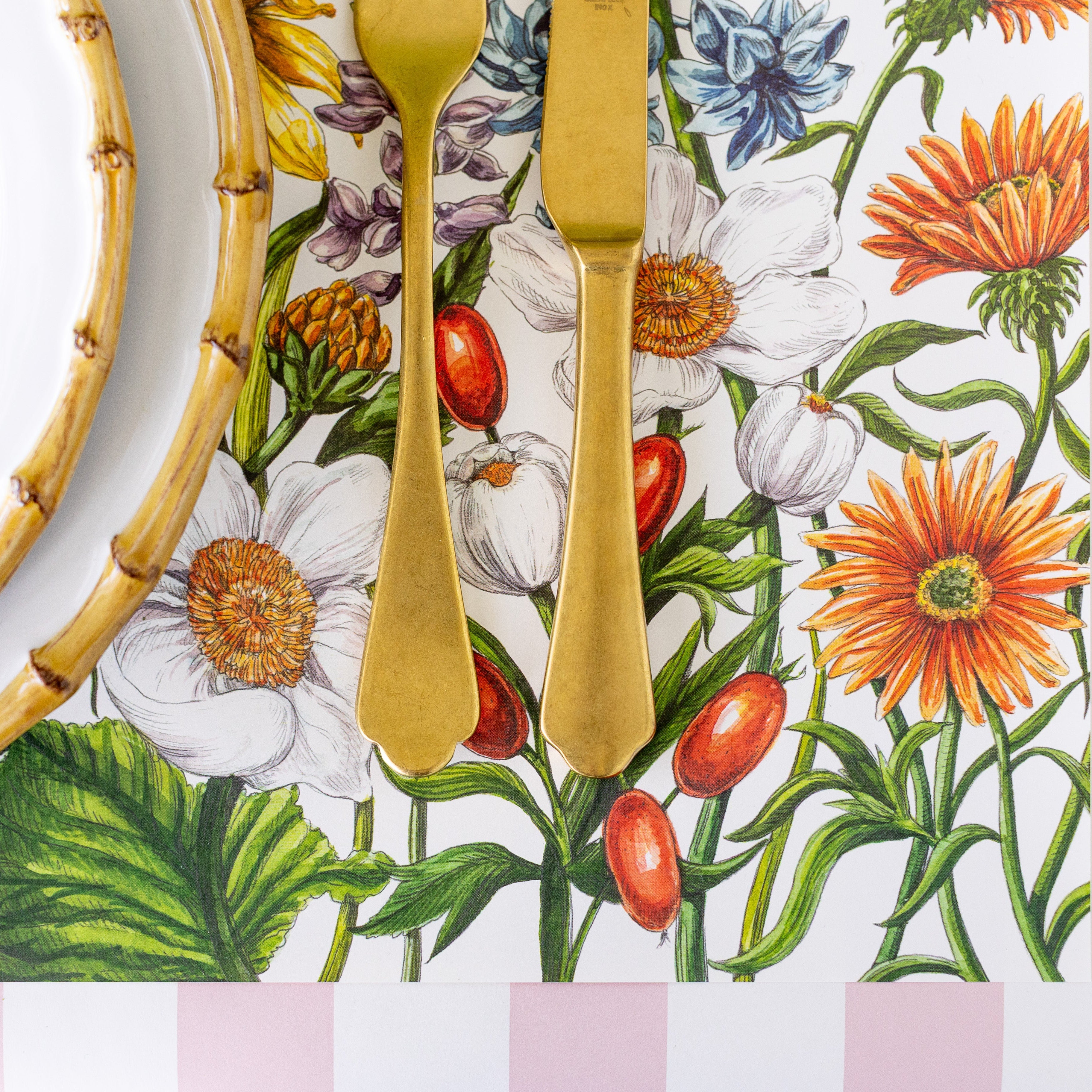 A close up of the Wildflower Meadow Placemat under bamboo dinnerware, gold flatware and Pink Classic Stripe Runner underneath.