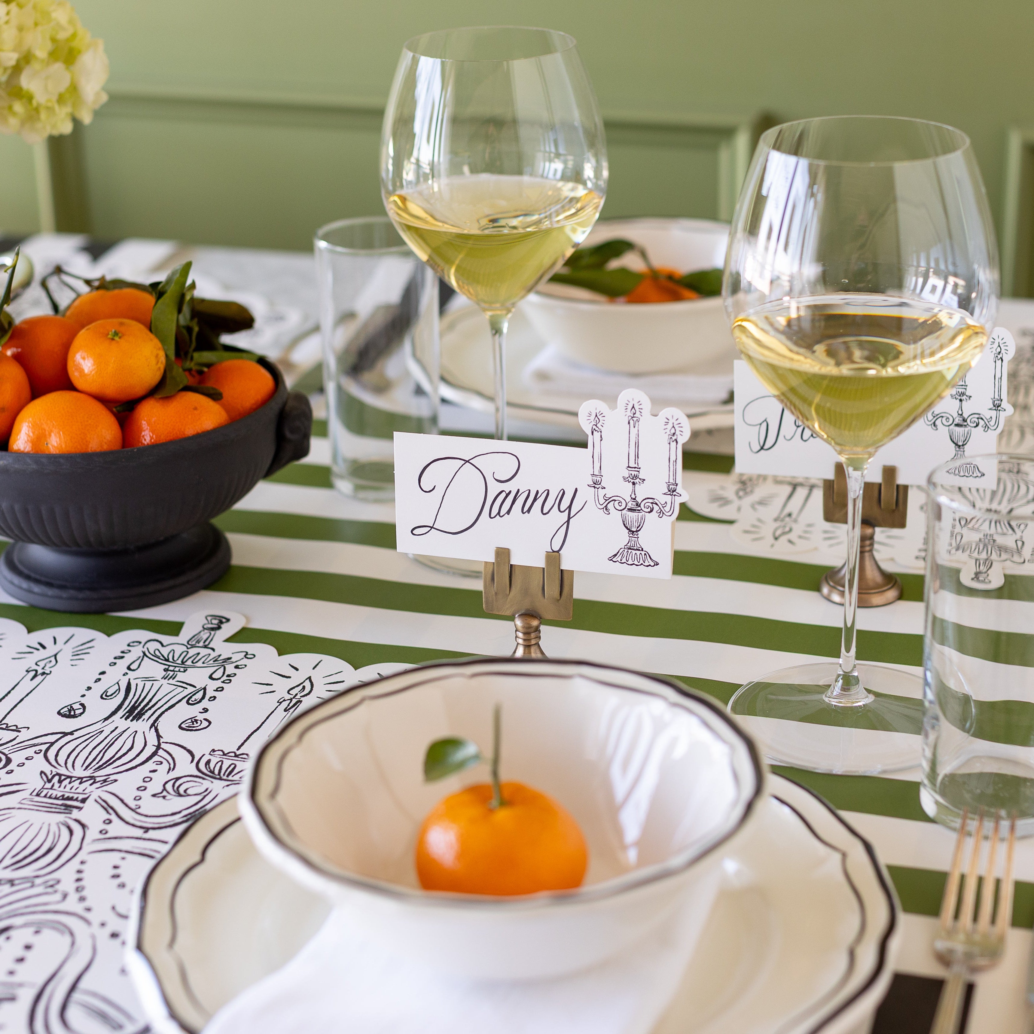 The Silver Place Card Holder holding up the Candelabra Place Card with "Danny" written on it, behind an elegant place setting.