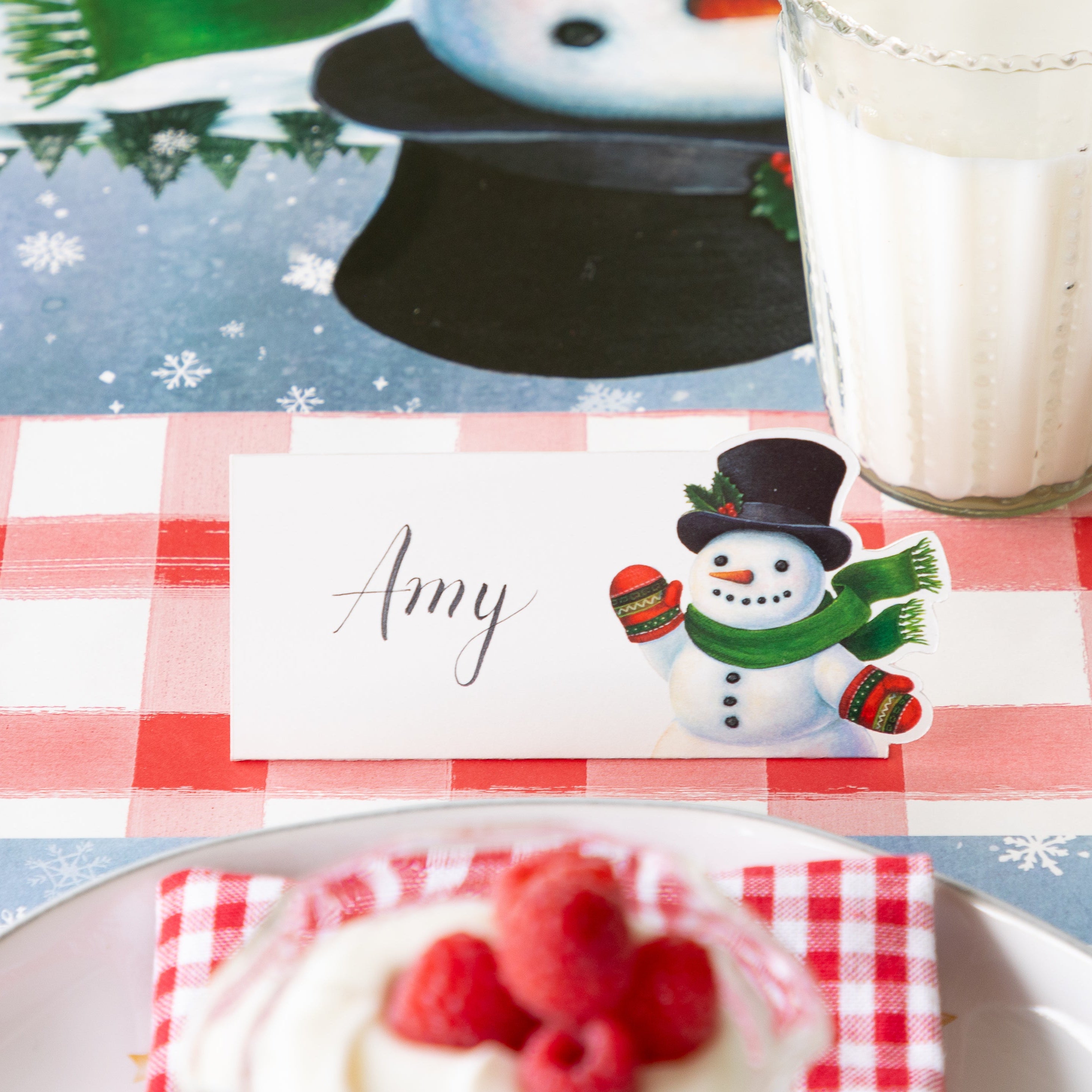 Snowman Place Card with "Amy" written in script on it, behind a festive place setting.