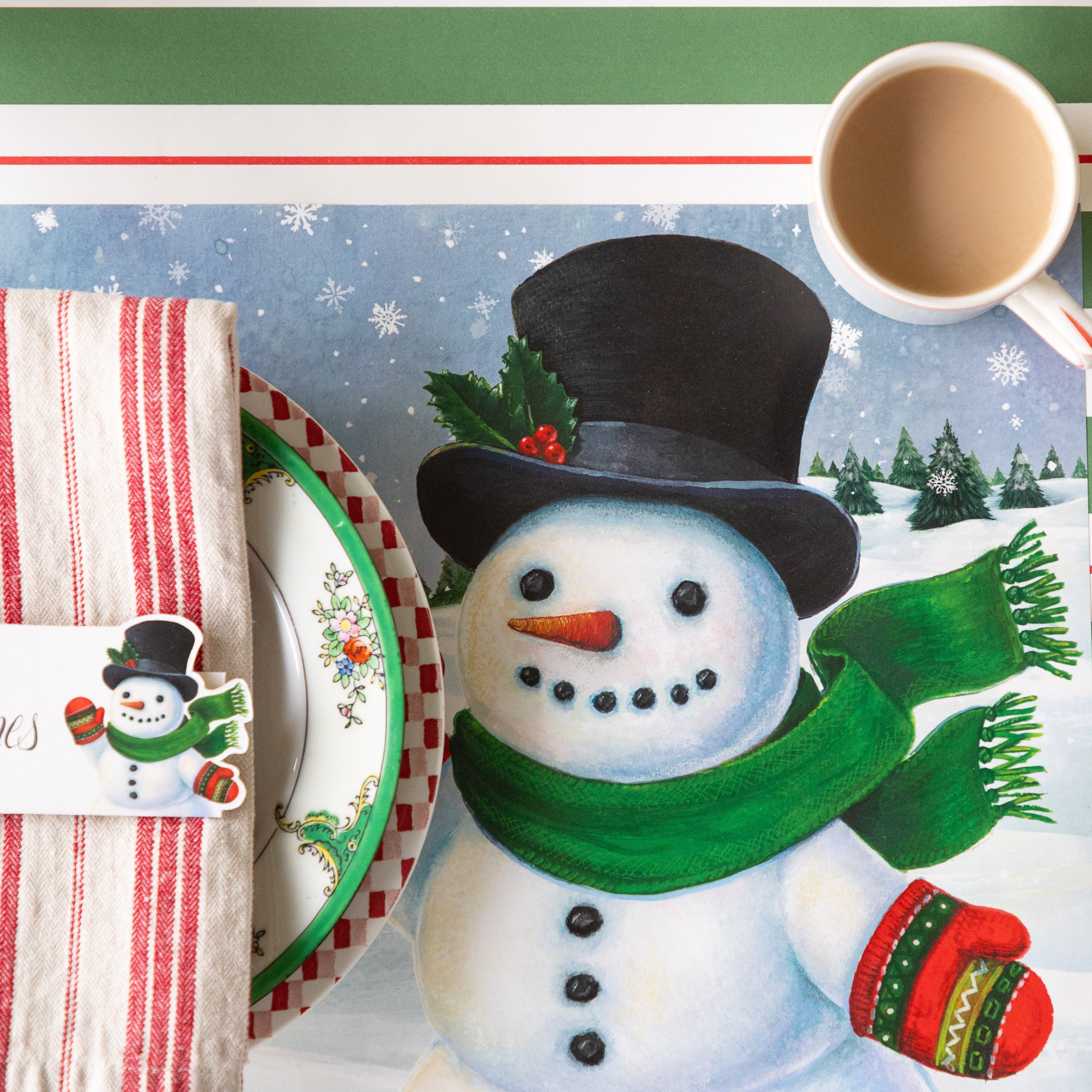 A place setting with a cup of coffee on the the Jolly Snowman Placemat, on the Green & Red Awning Stripe Runner.