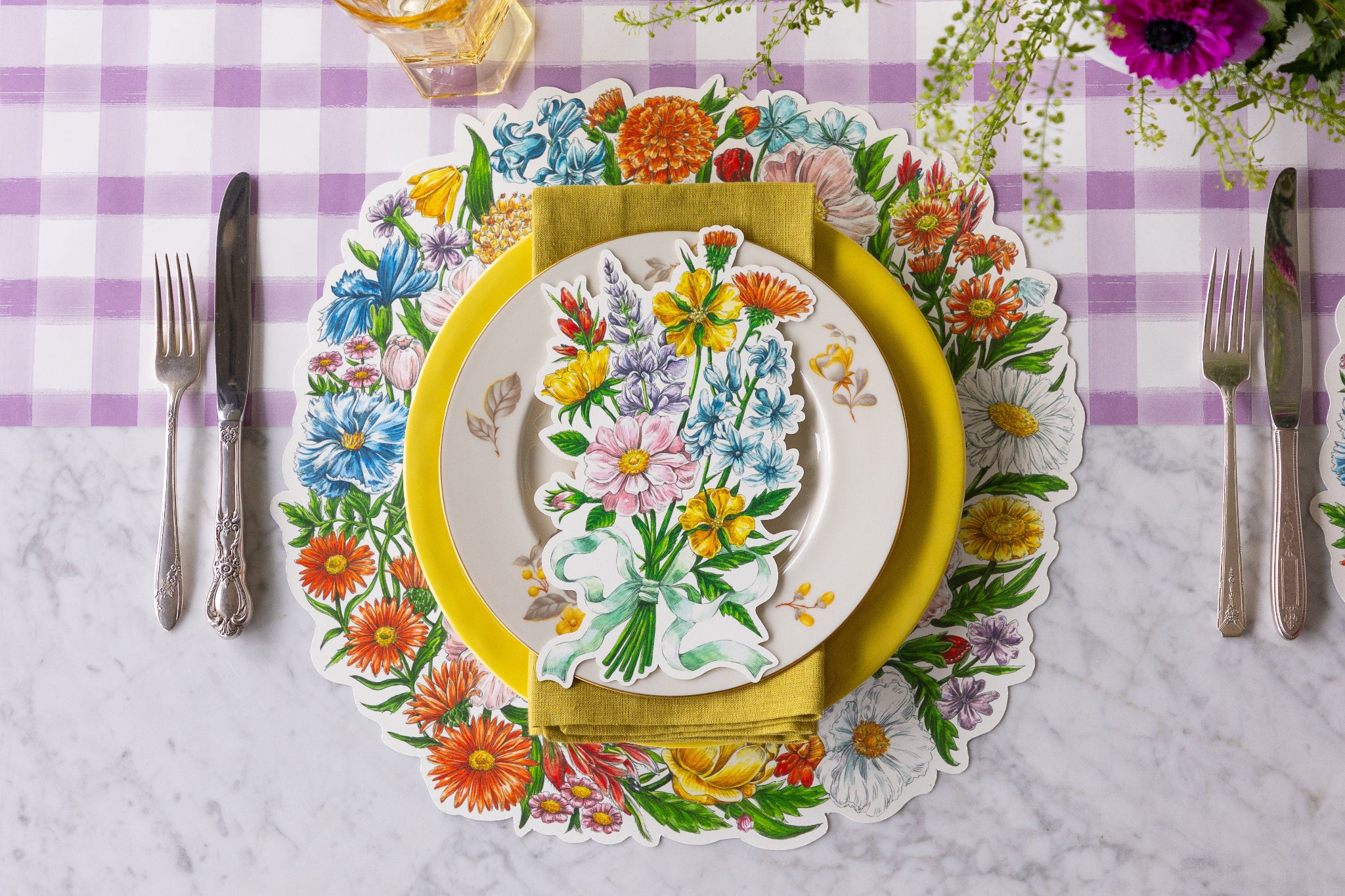Table setting with Die-cut Wildflower Wreath Placemat, Wildflower Table Accent and colorful plates on the Lilac Painted Check Runner.