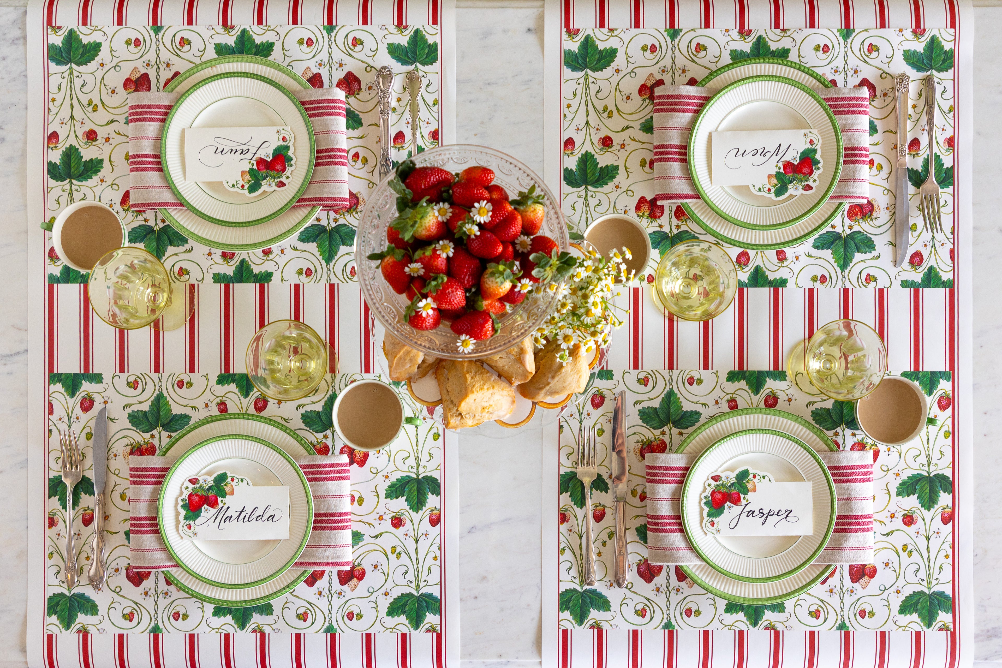 Table setting with strawbeerries, scones and flowers, the Strawberry Fields Placemat, green rimmed plates, red striped napkin, Strawberries Place Card and vintage cutlery on the Red Linen Stripe Runner.